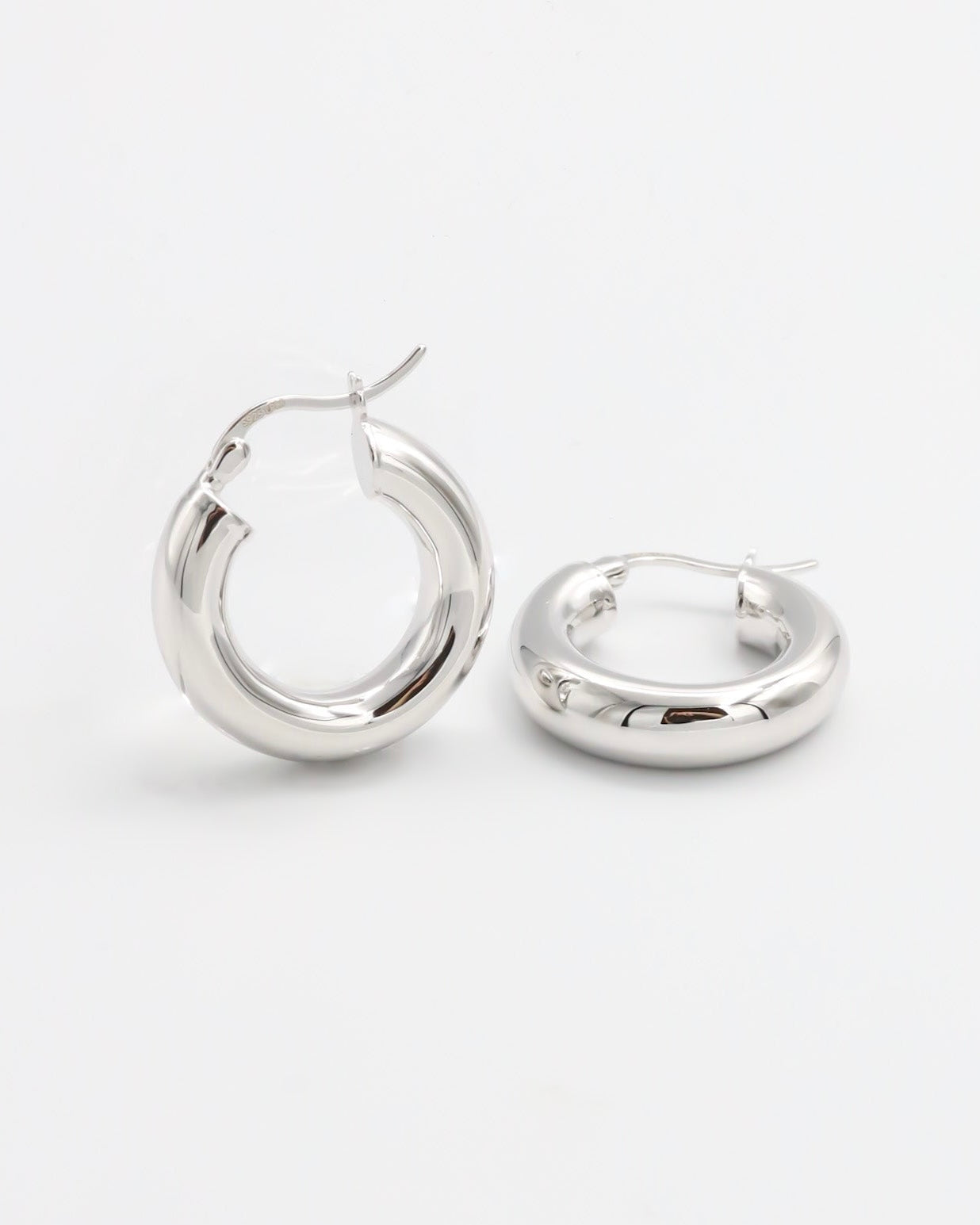 A pair of silver hoop earrings with a latch back closure mechanism, displayed on a white background.