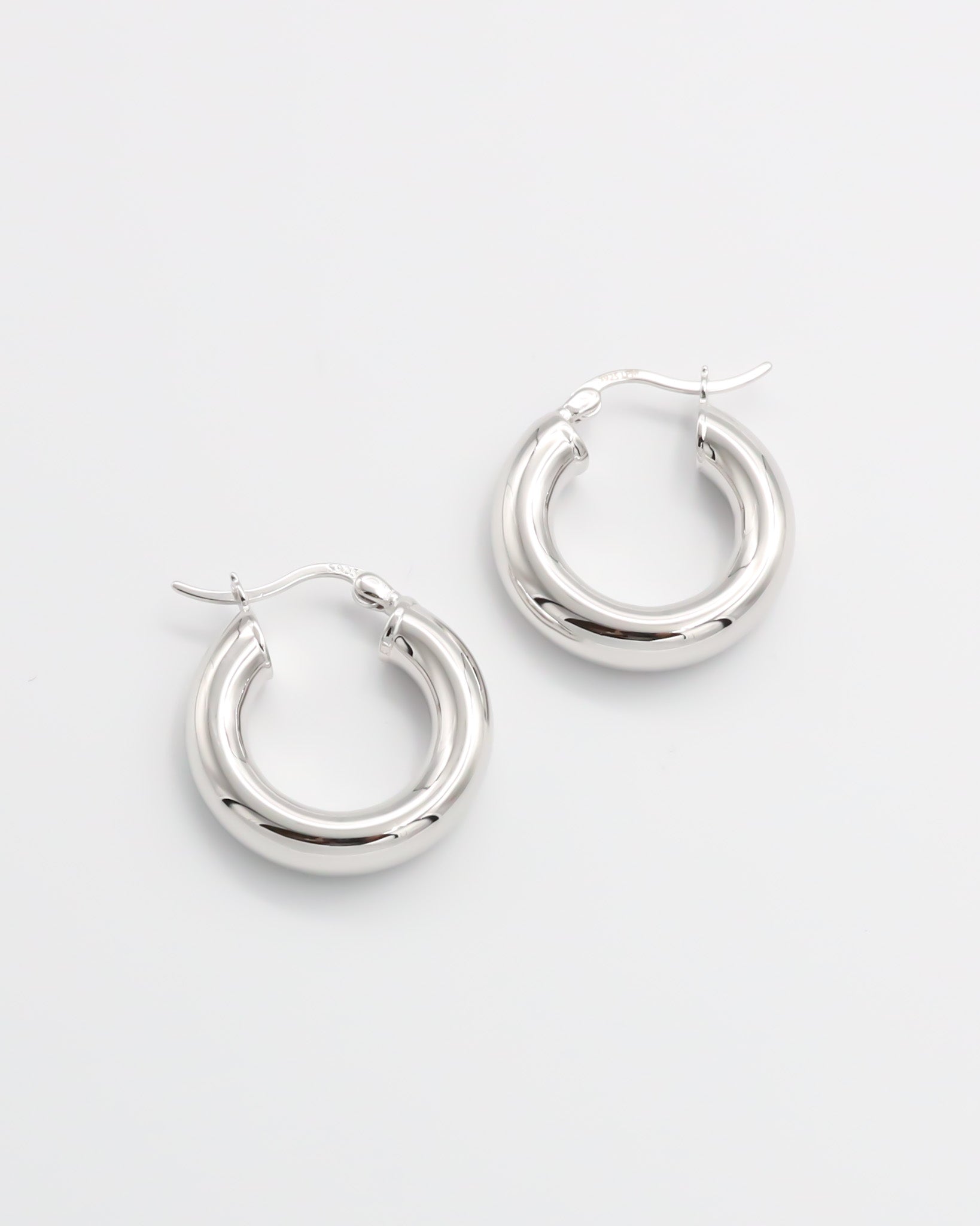 A pair of silver hoop earrings with a latch back closure mechanism, displayed on a white background.