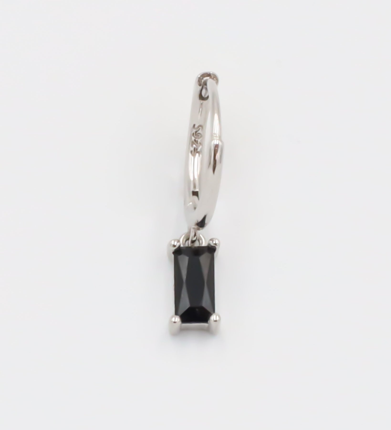 A black and silver colored hoop earring with a hinged clasp.