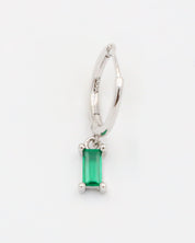 A silver hoop earring with a green gemstone attached to it.