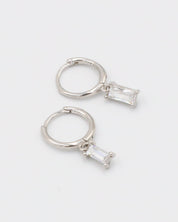 A silver hoop earring with a white stone pendant attached to it, displayed against a white background.
