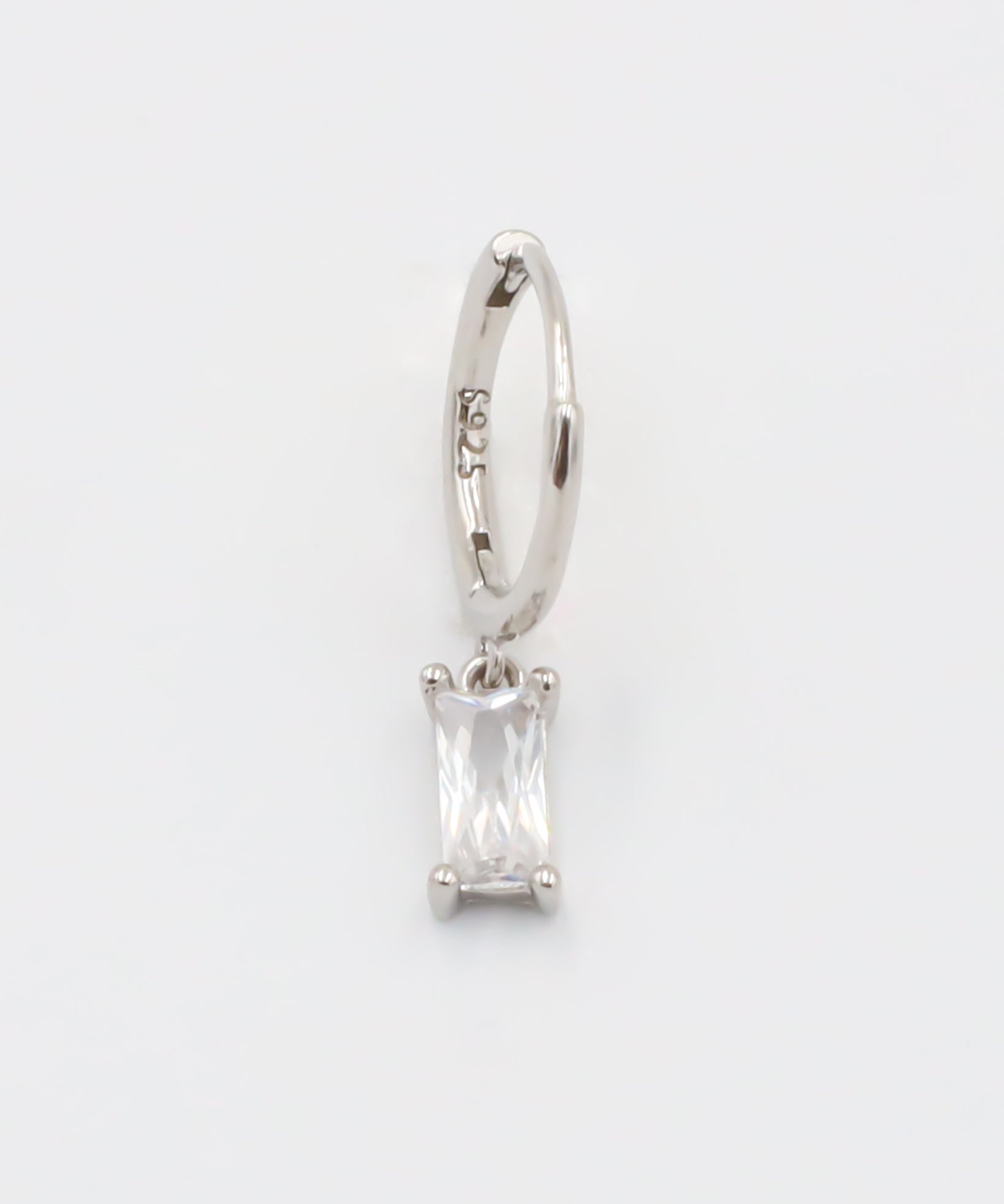 A silver hoop earring with a white stone pendant attached to it, displayed against a white background.