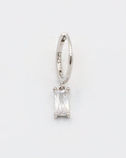A silver hoop earring with a white stone pendant attached to it, displayed against a white background.