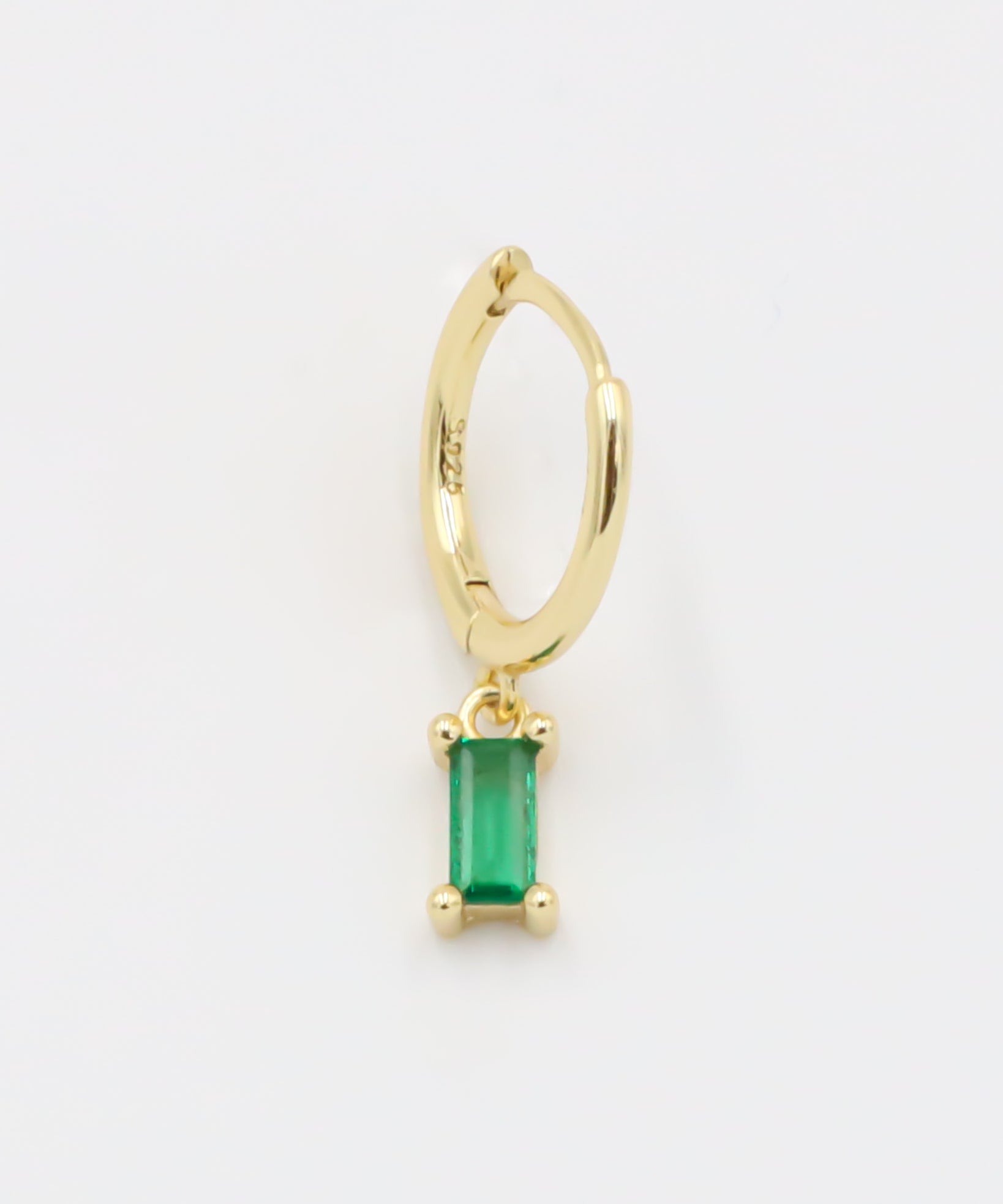 A gold-colored hoop earring with a green square pendant attached to it.