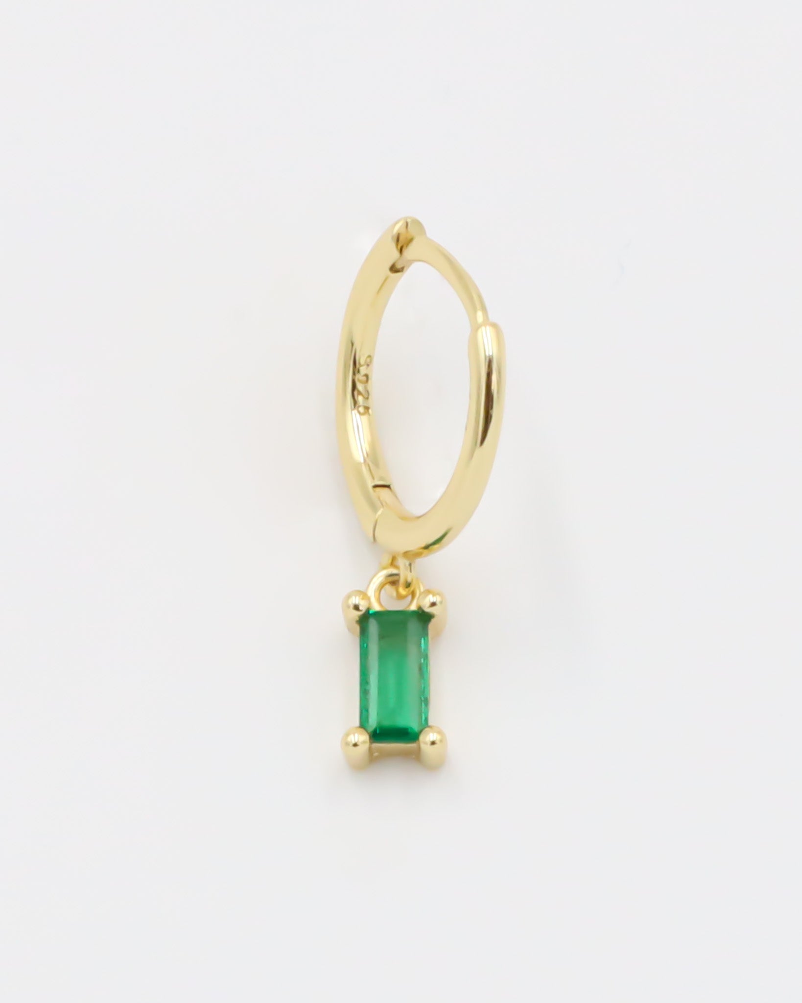 A gold-colored hoop earring with a green square pendant attached to it.