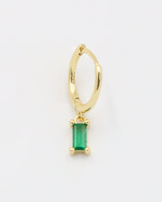 A gold-colored hoop earring with a green square pendant attached to it.