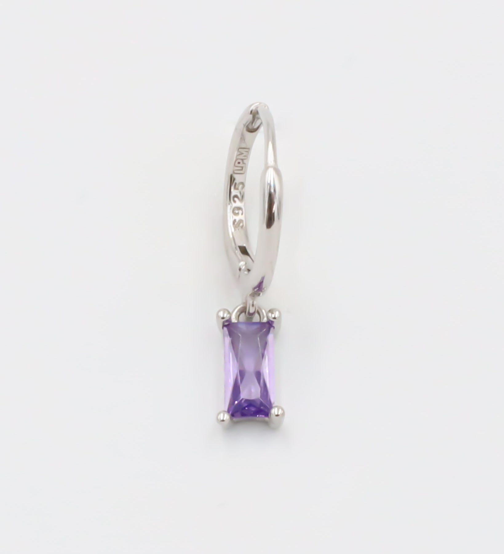 A silver hoop earring with a purple gemstone attached to it, displayed against a white background.