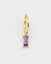 A gold-colored hoop earring with a purple gemstone attached to it, displayed against a white background.