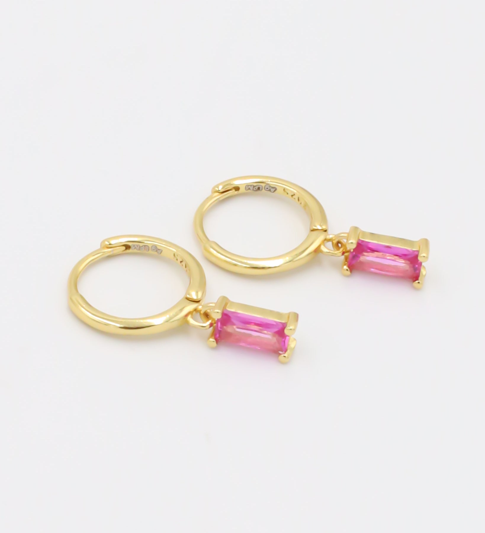 A single pink gemstone earring attached to a gold-colored hoop, presented against a white background.