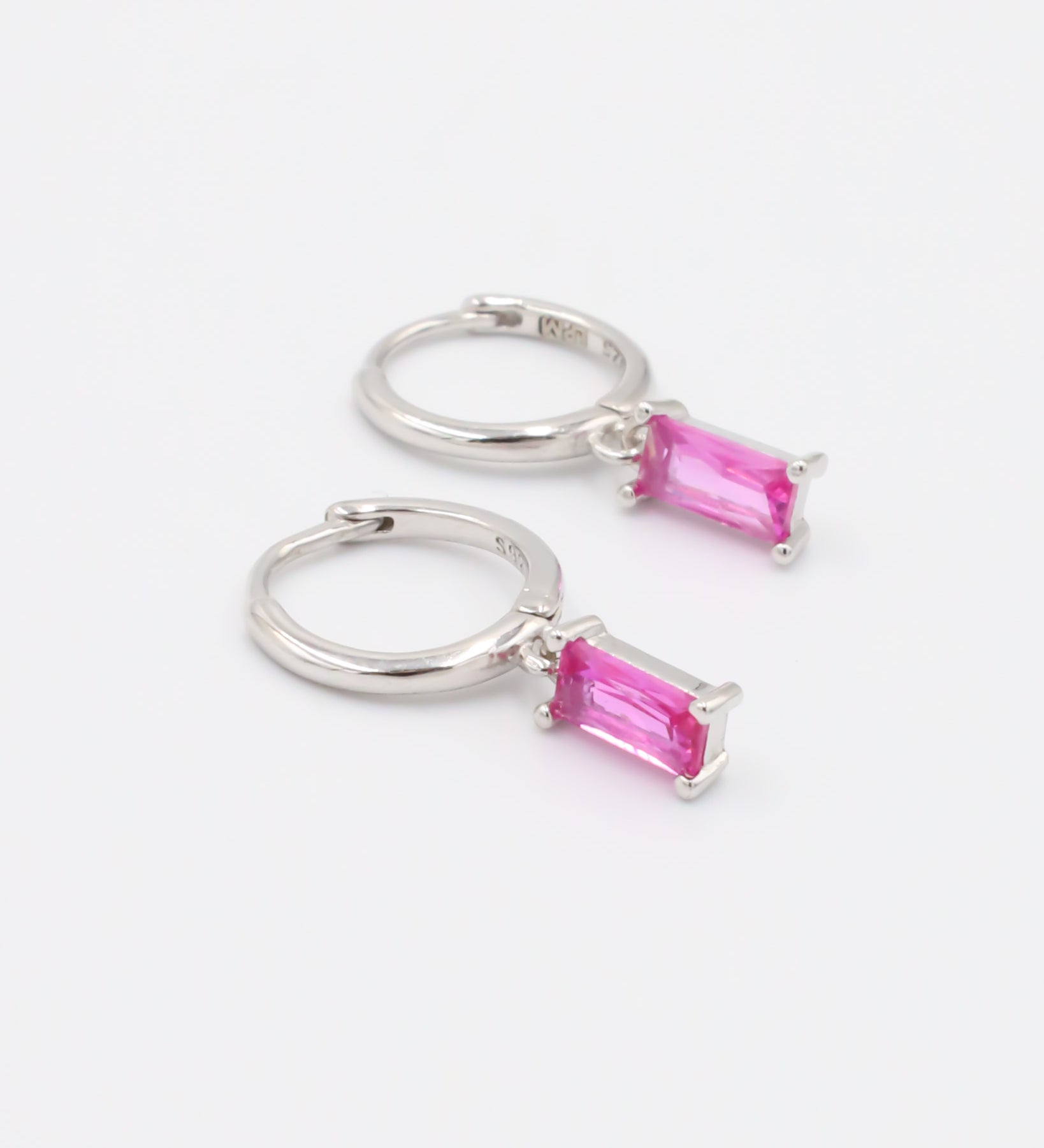 A pink and silver colored hoop earring with a hinged clasp.