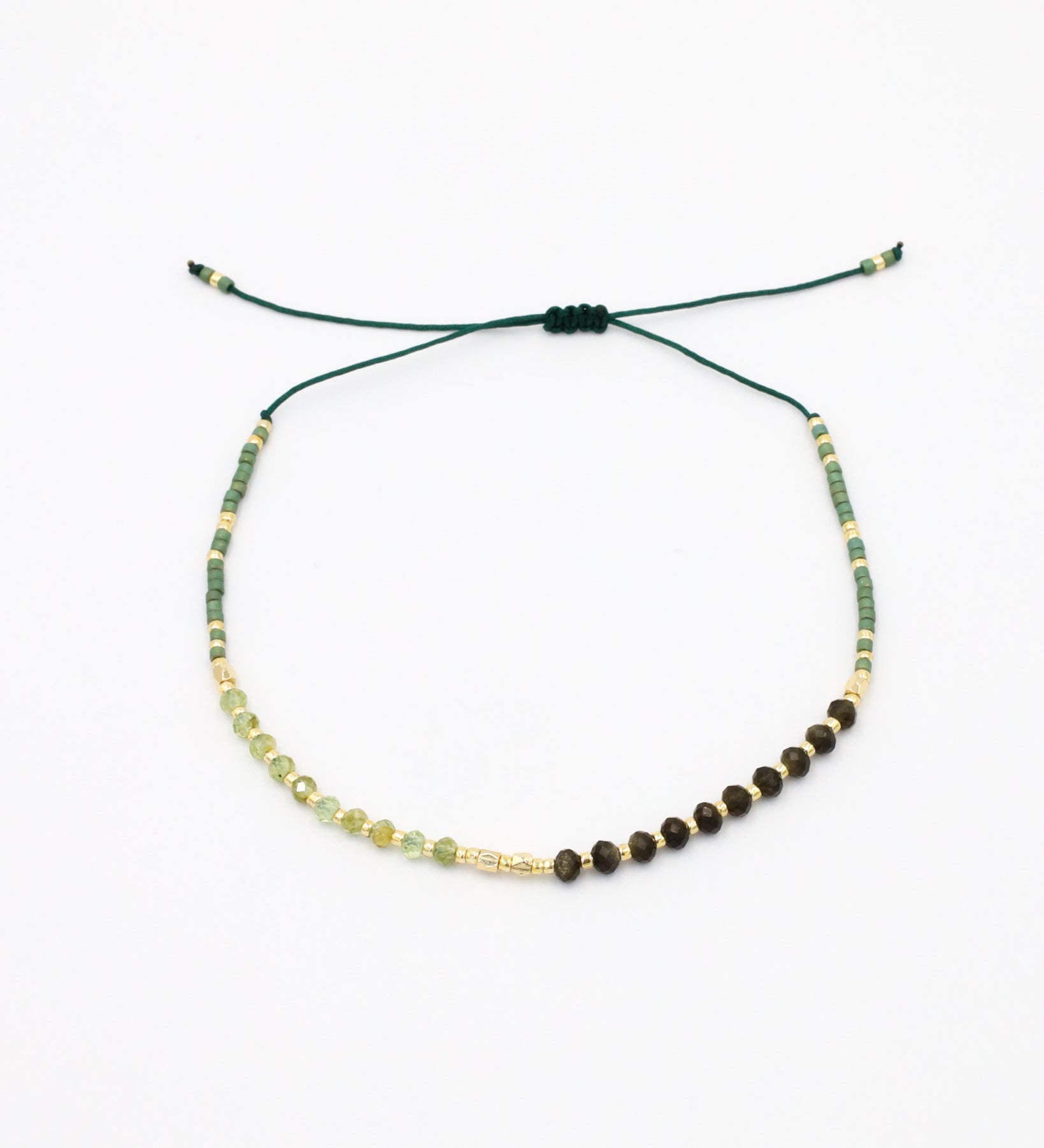 A beaded bracelet with a mix of green, gold, and brown colors, featuring rhinestones and an adjustable cord.