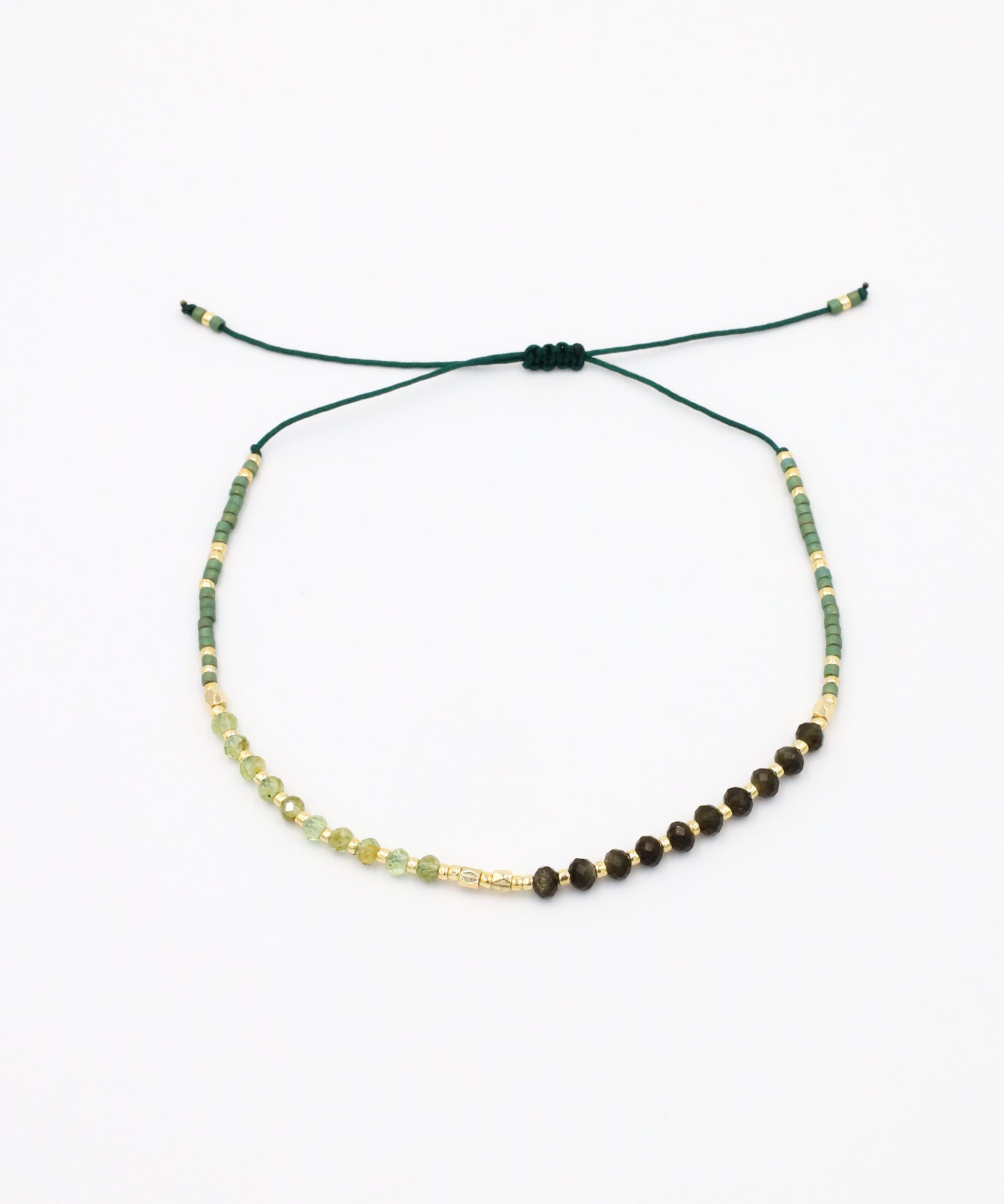 A beaded bracelet with a mix of green, gold, and brown colors, featuring rhinestones and an adjustable cord.