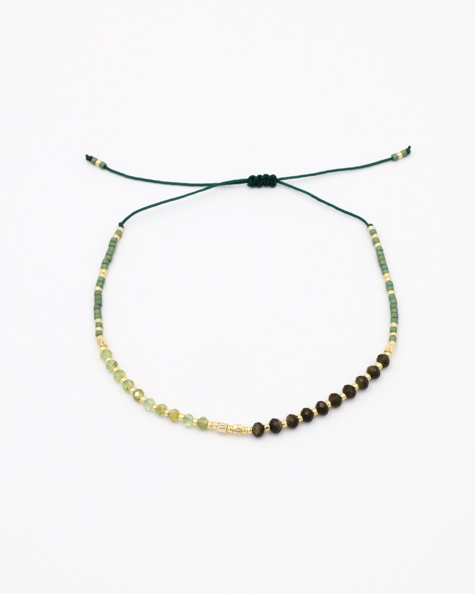 A beaded bracelet with a mix of green, gold, and brown colors, featuring rhinestones and an adjustable cord.