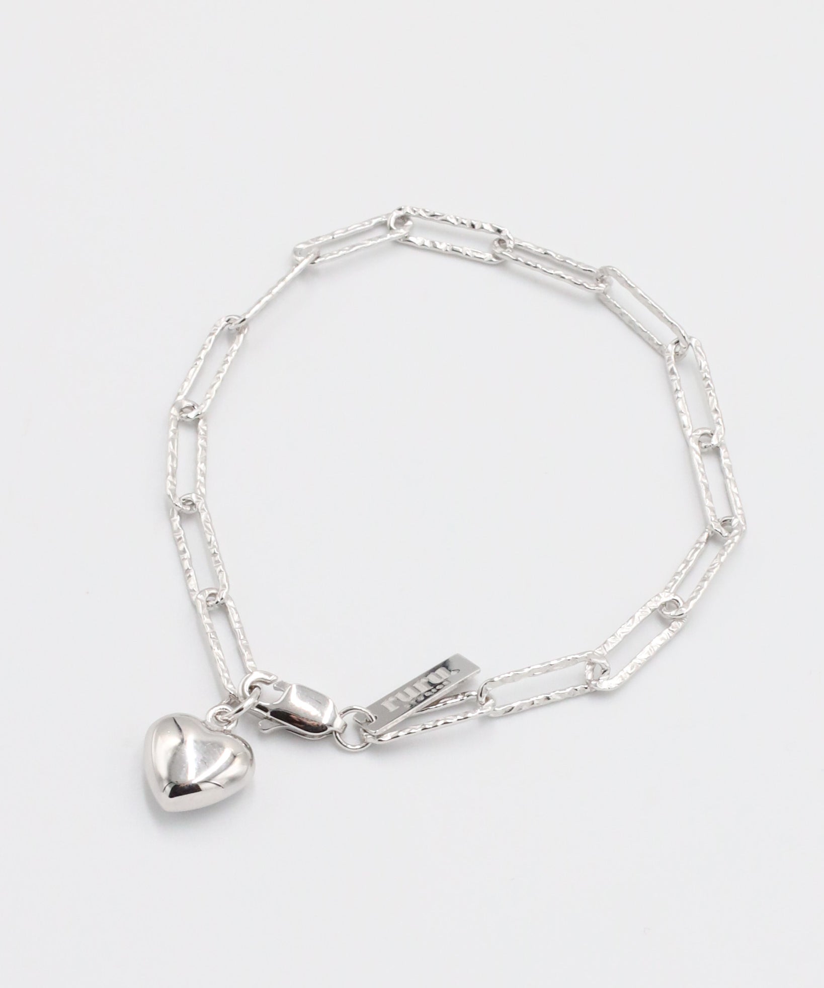 A silver bracelet with a heart-shaped charm on a white background.