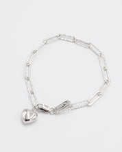 A silver bracelet with a heart-shaped charm on a white background.