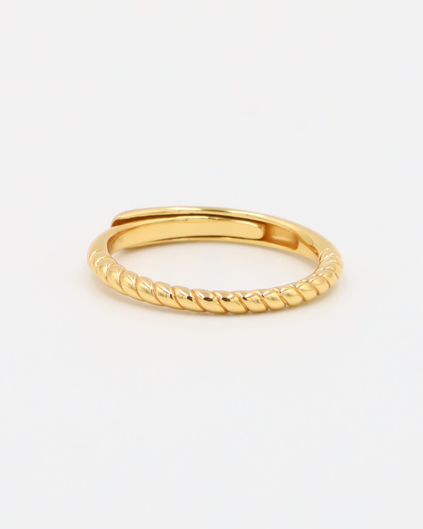 A gold-colored ring with a textured band, displayed against a white background.