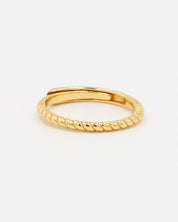 A gold-colored ring with a textured band, displayed against a white background.