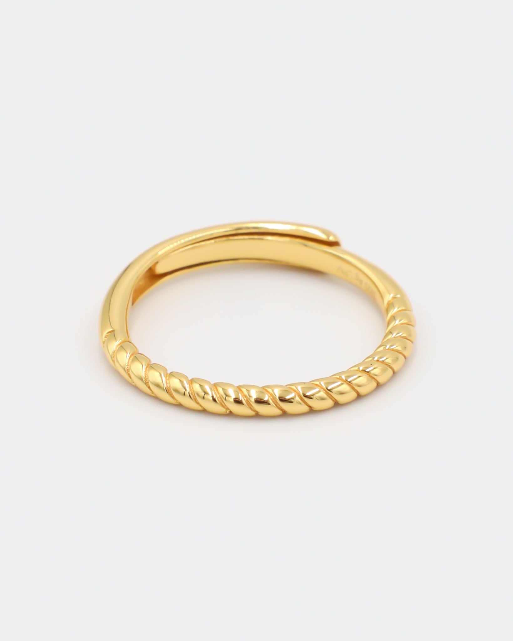 A gold-colored ring with a textured band, displayed against a white background.