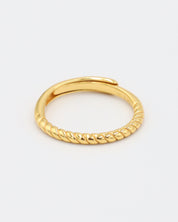 A gold-colored ring with a textured band, displayed against a white background.