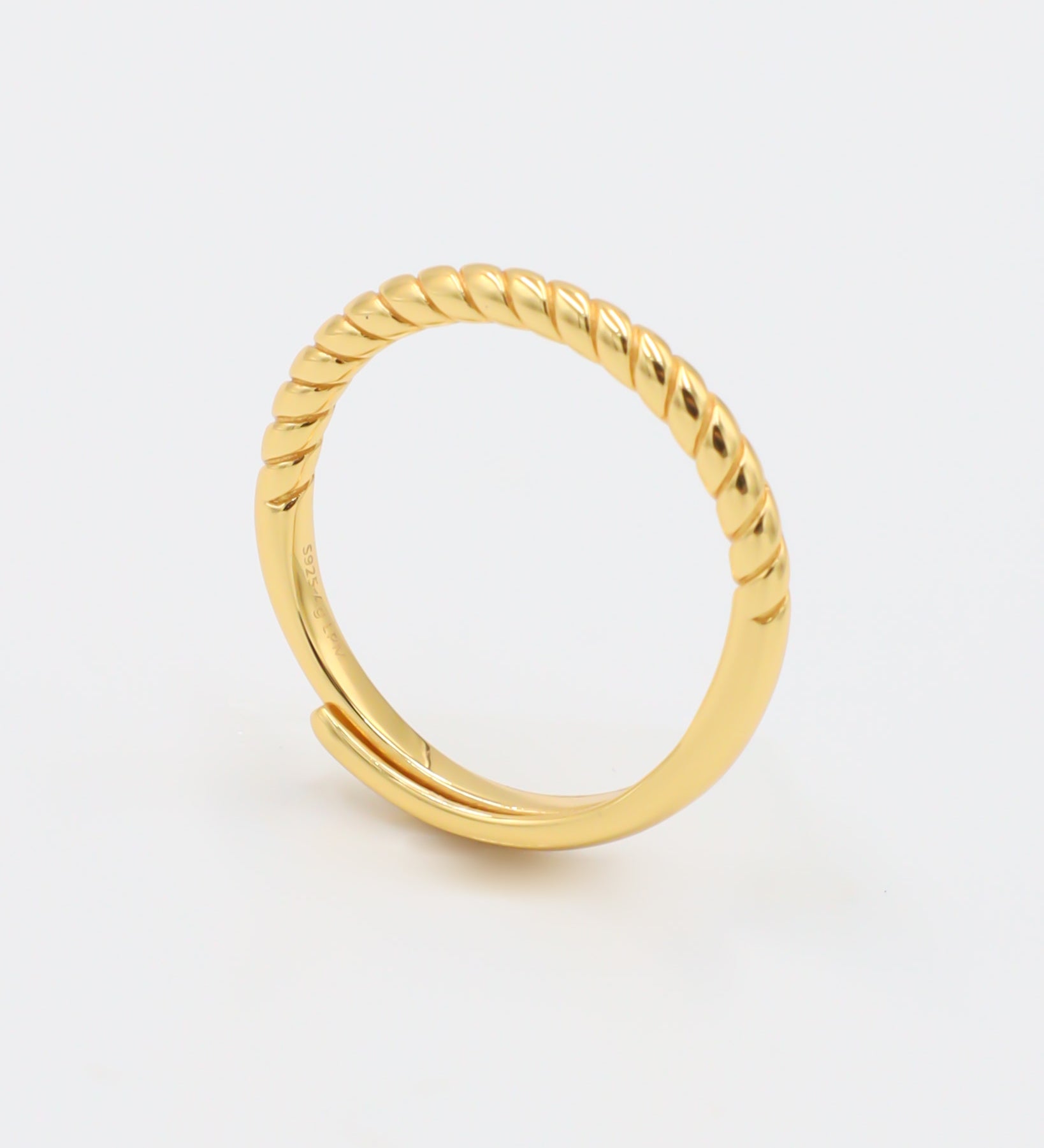 A gold-colored ring with a textured band, displayed against a white background.