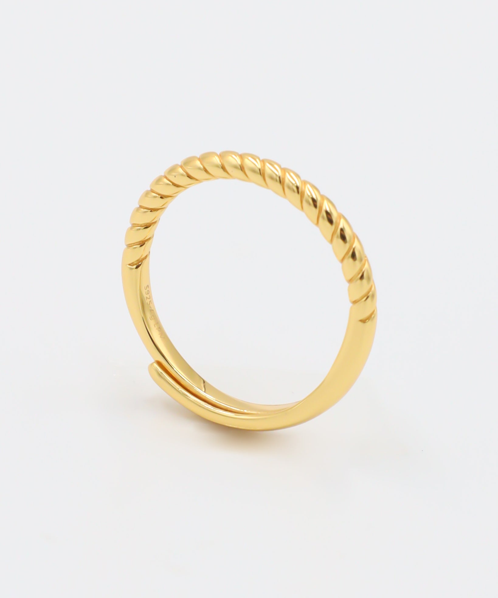 A gold-colored ring with a textured band, displayed against a white background.