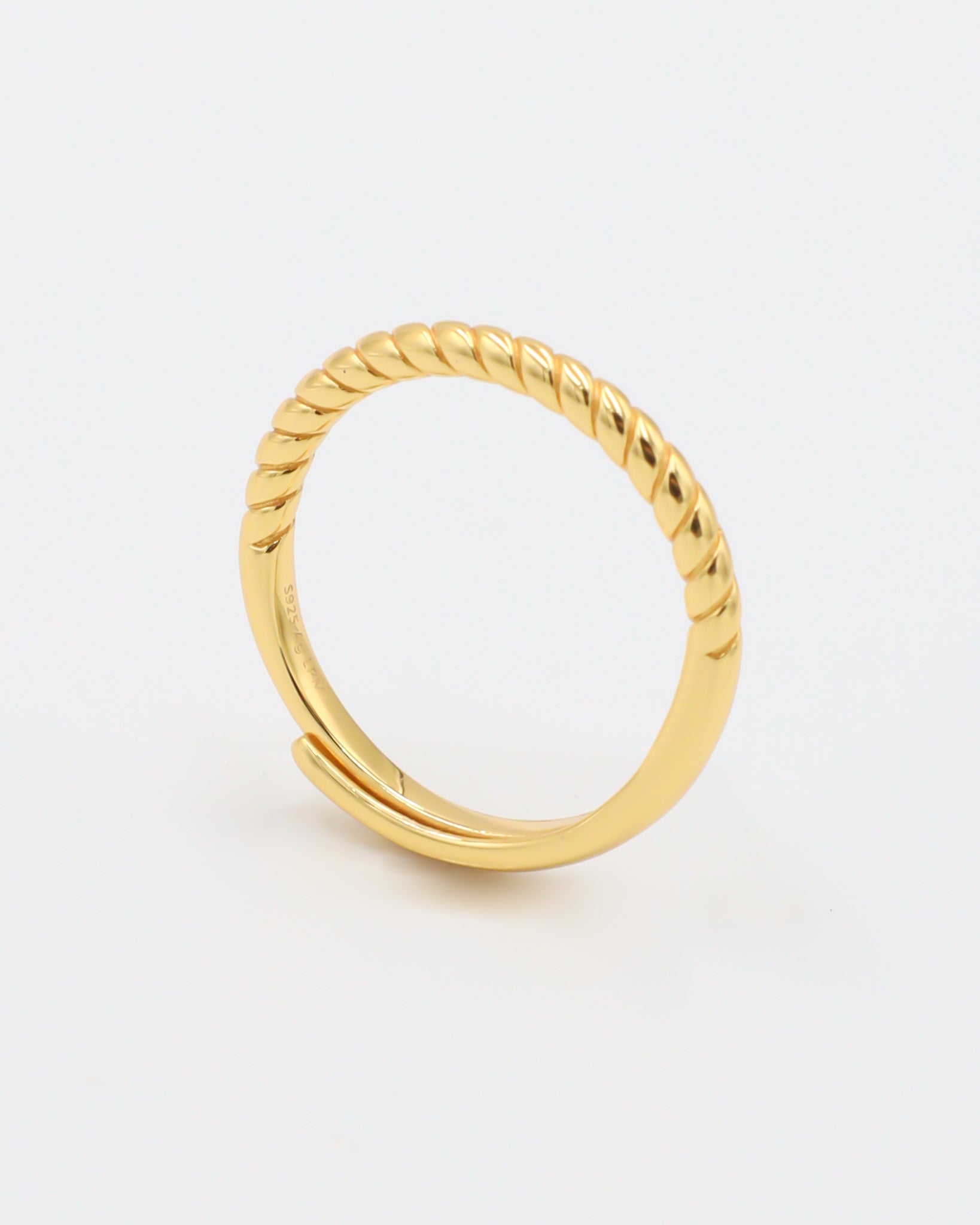 A gold-colored ring with a textured band, displayed against a white background.