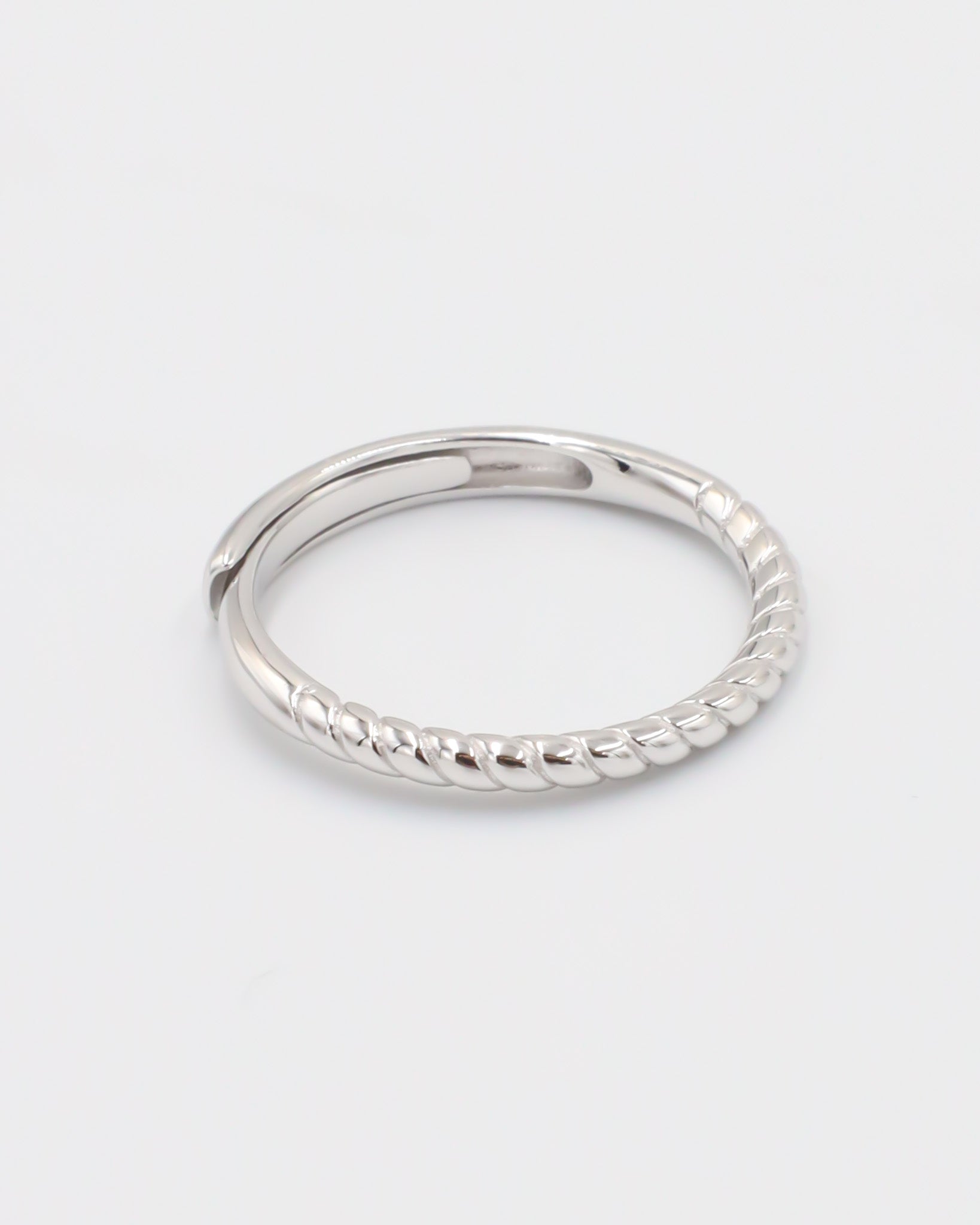 A silver ring with a twisted band design on a white background.