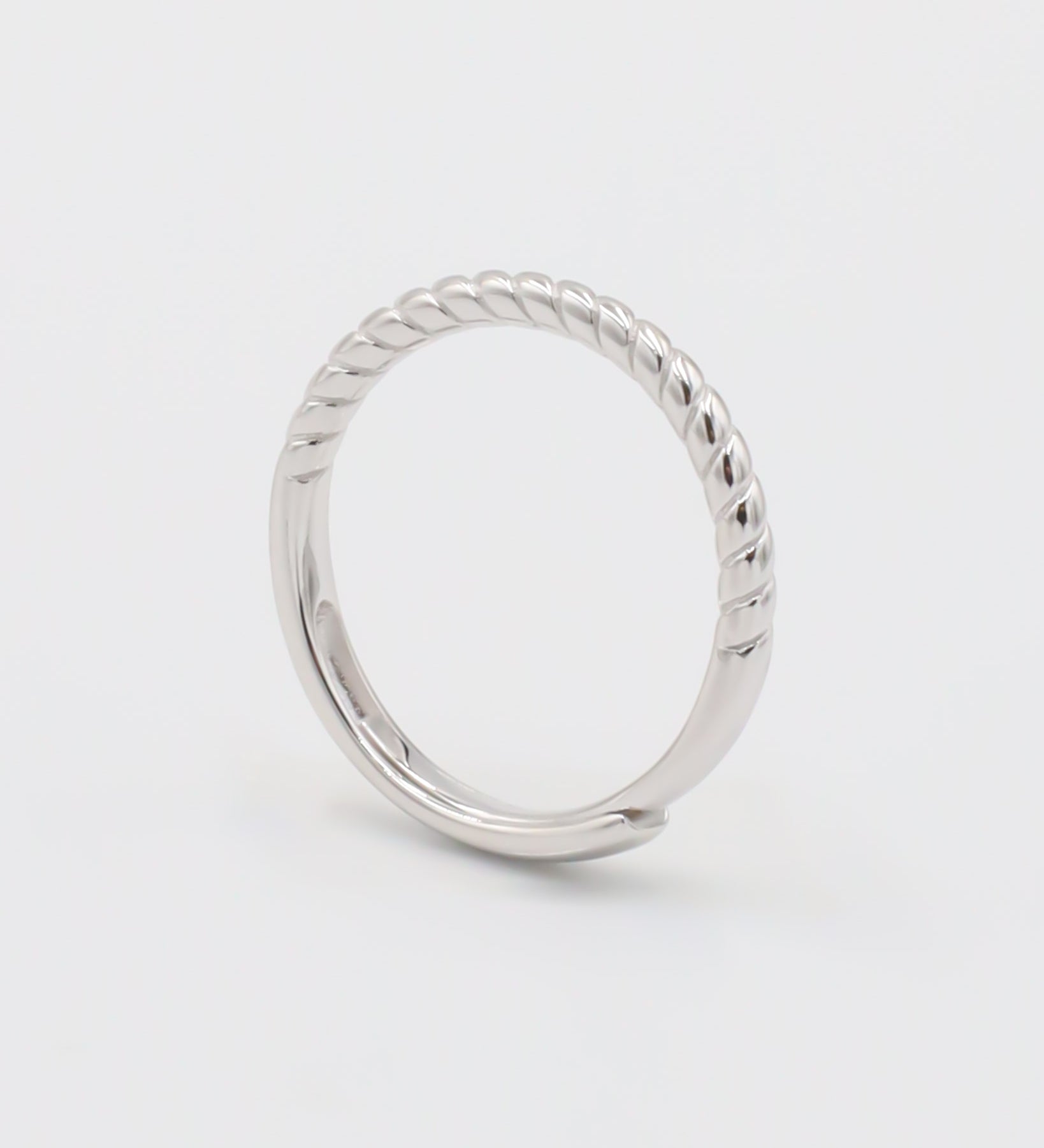 A silver ring with a twisted band design on a white background.