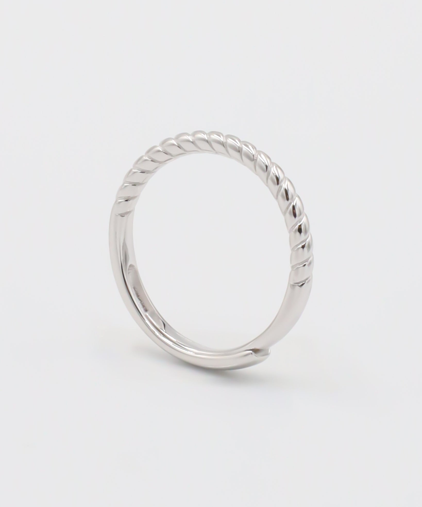 A silver ring with a twisted band design on a white background.