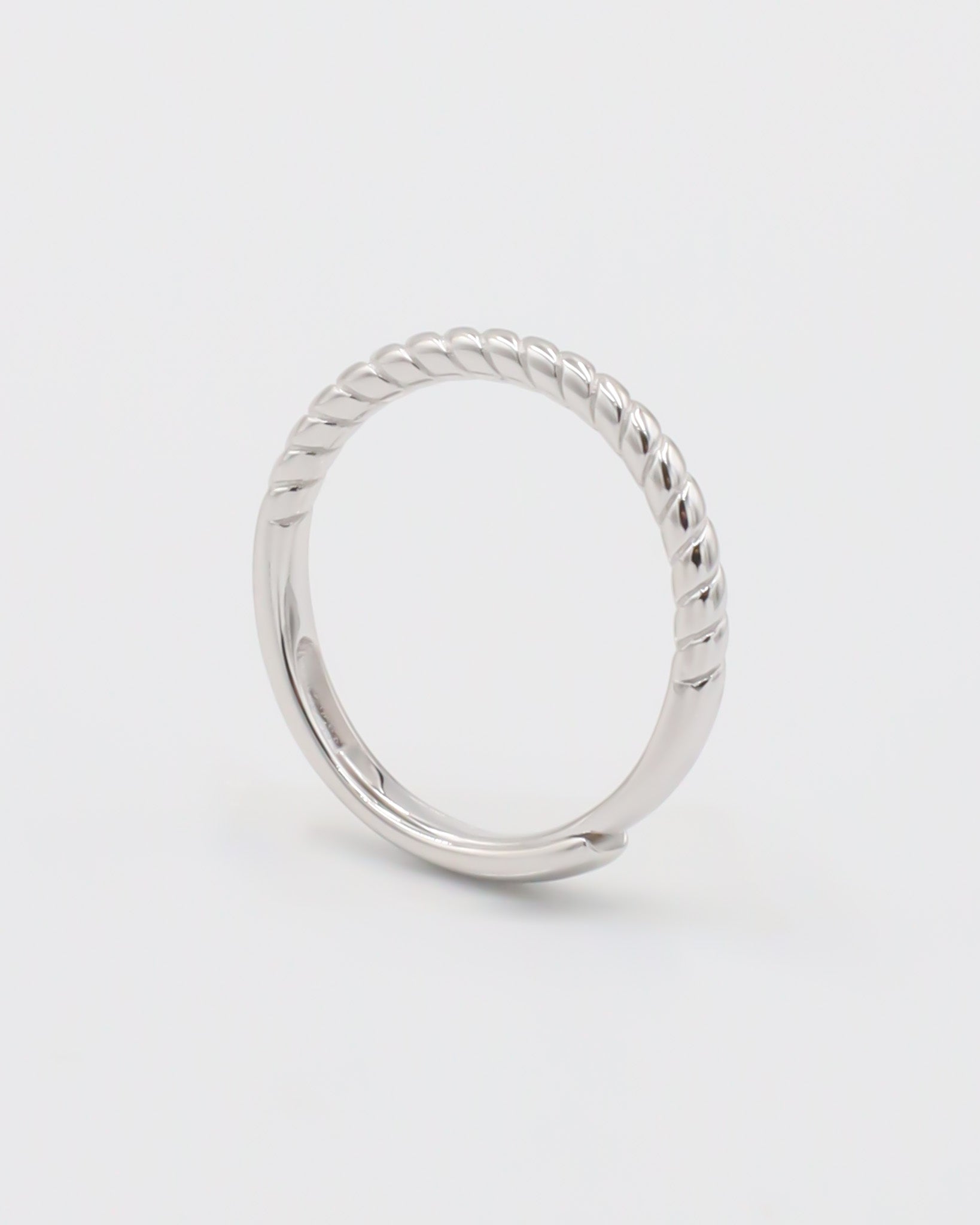 A silver ring with a twisted band design on a white background.