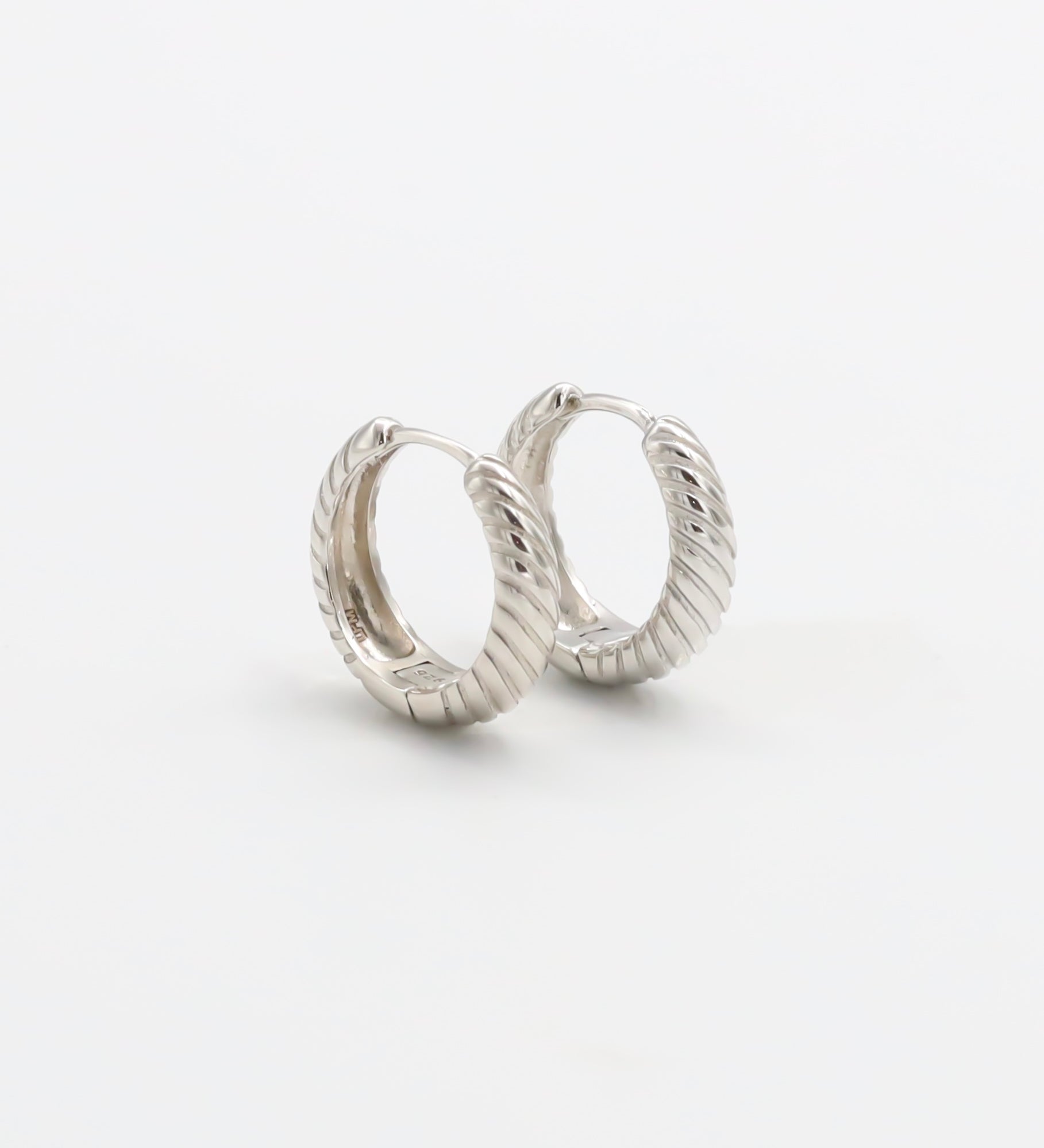 A pair of silver hoop earrings with a hinged clasp, displayed against a white background.
