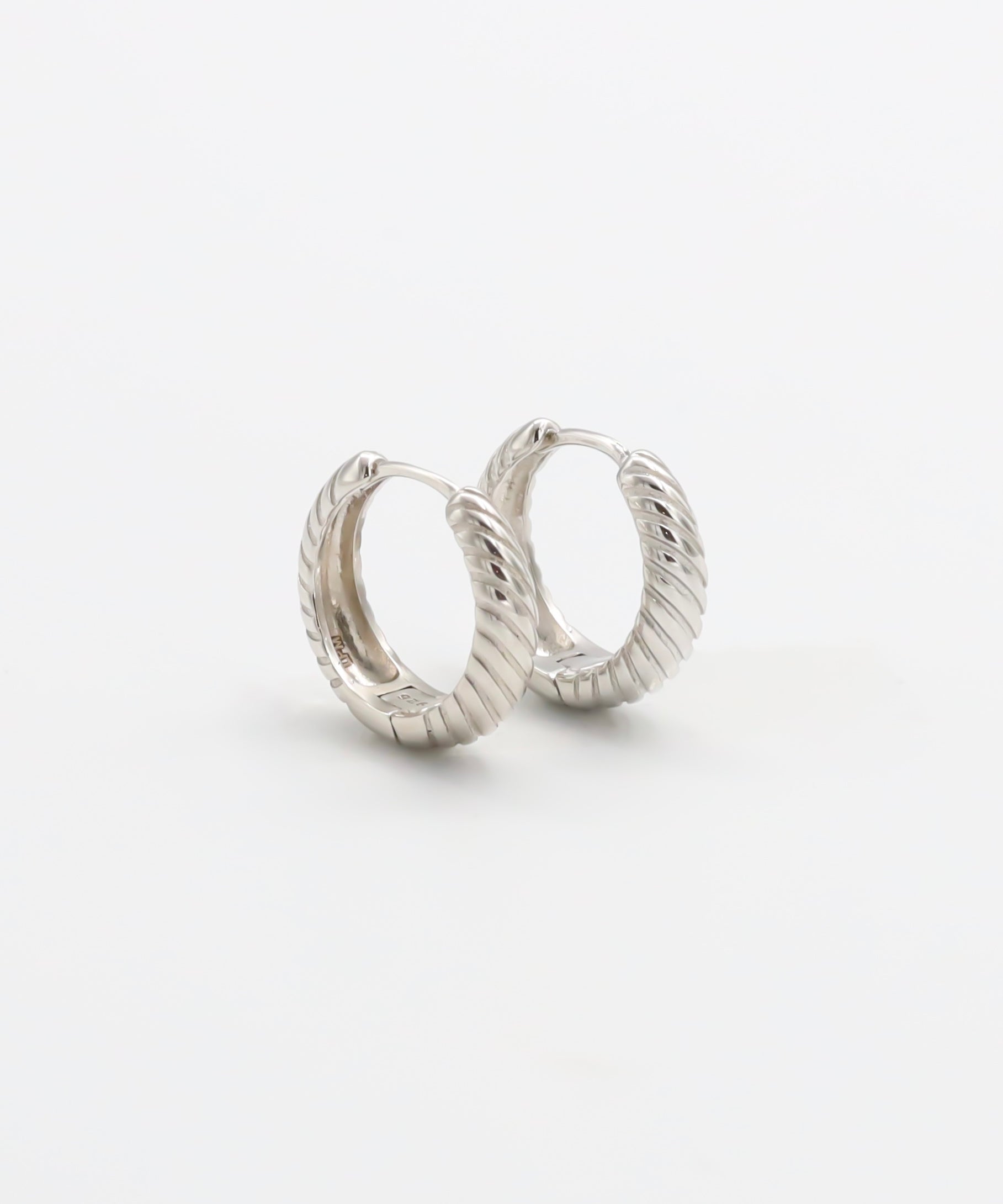 A pair of silver hoop earrings with a hinged clasp, displayed against a white background.