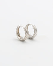 A pair of silver hoop earrings with a hinged clasp, displayed against a white background.