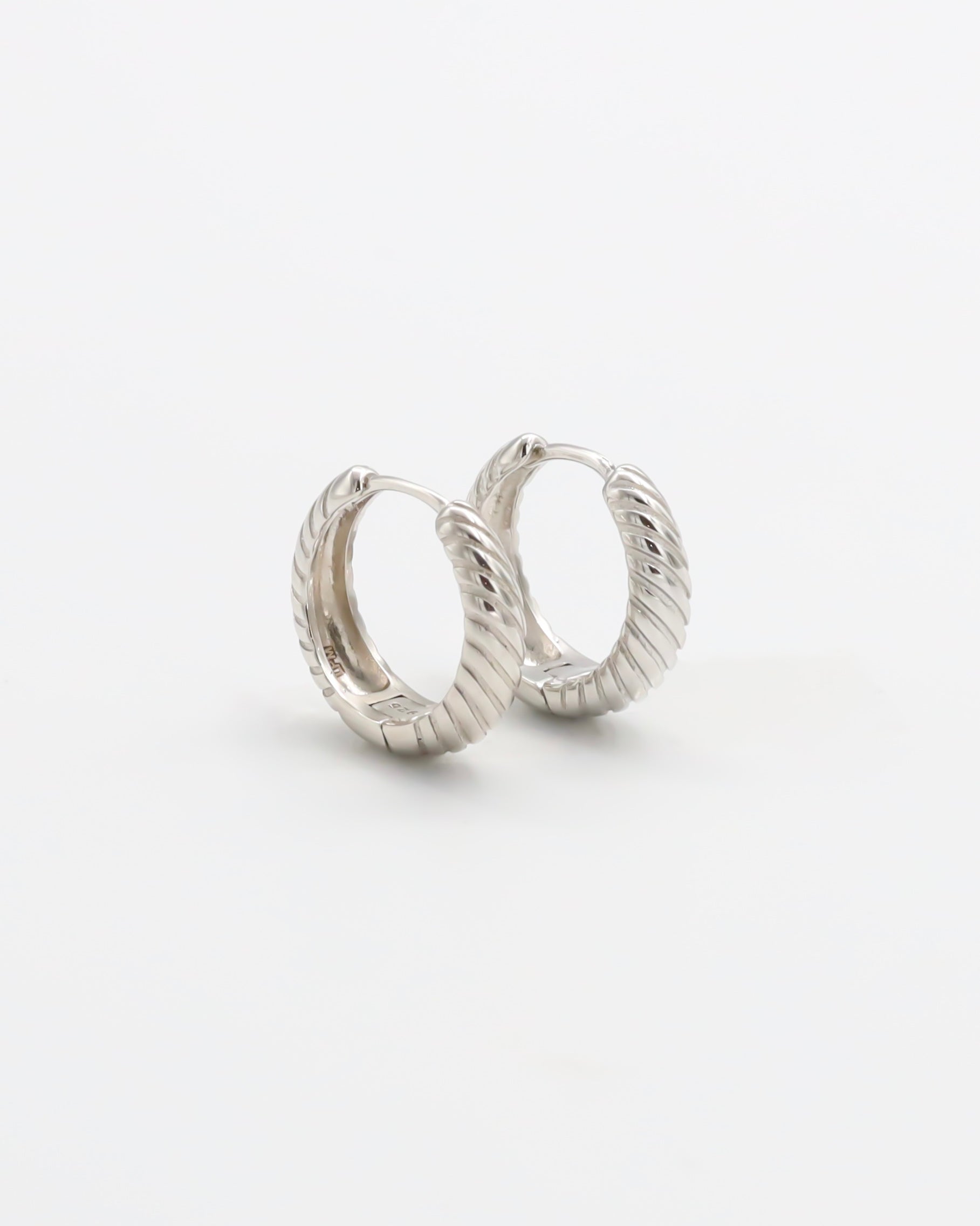 A pair of silver hoop earrings with a hinged clasp, displayed against a white background.