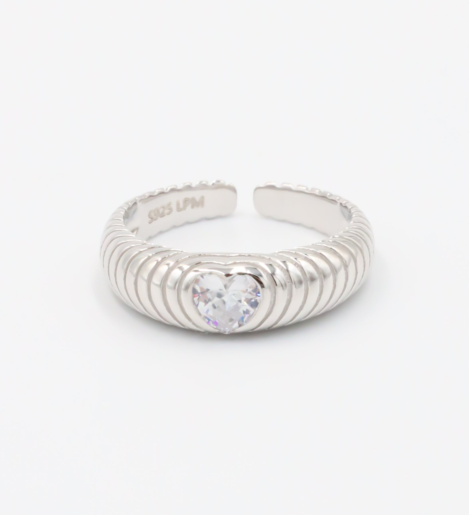 A silver ring with a heart-shaped stone in the center, featuring a textured band and a brightly colored stone.