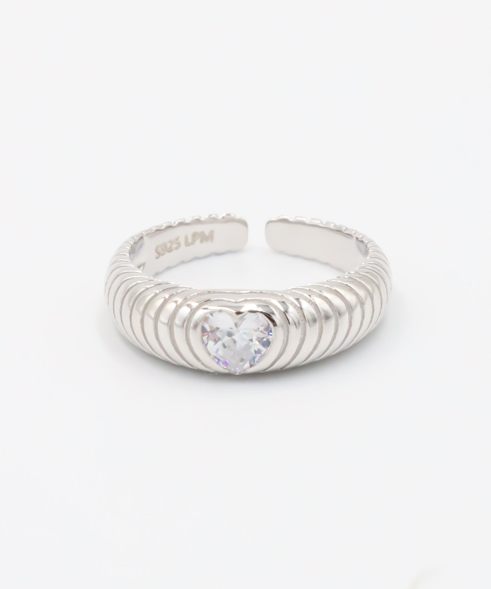 A silver ring with a heart-shaped stone in the center, featuring a textured band and a brightly colored stone.