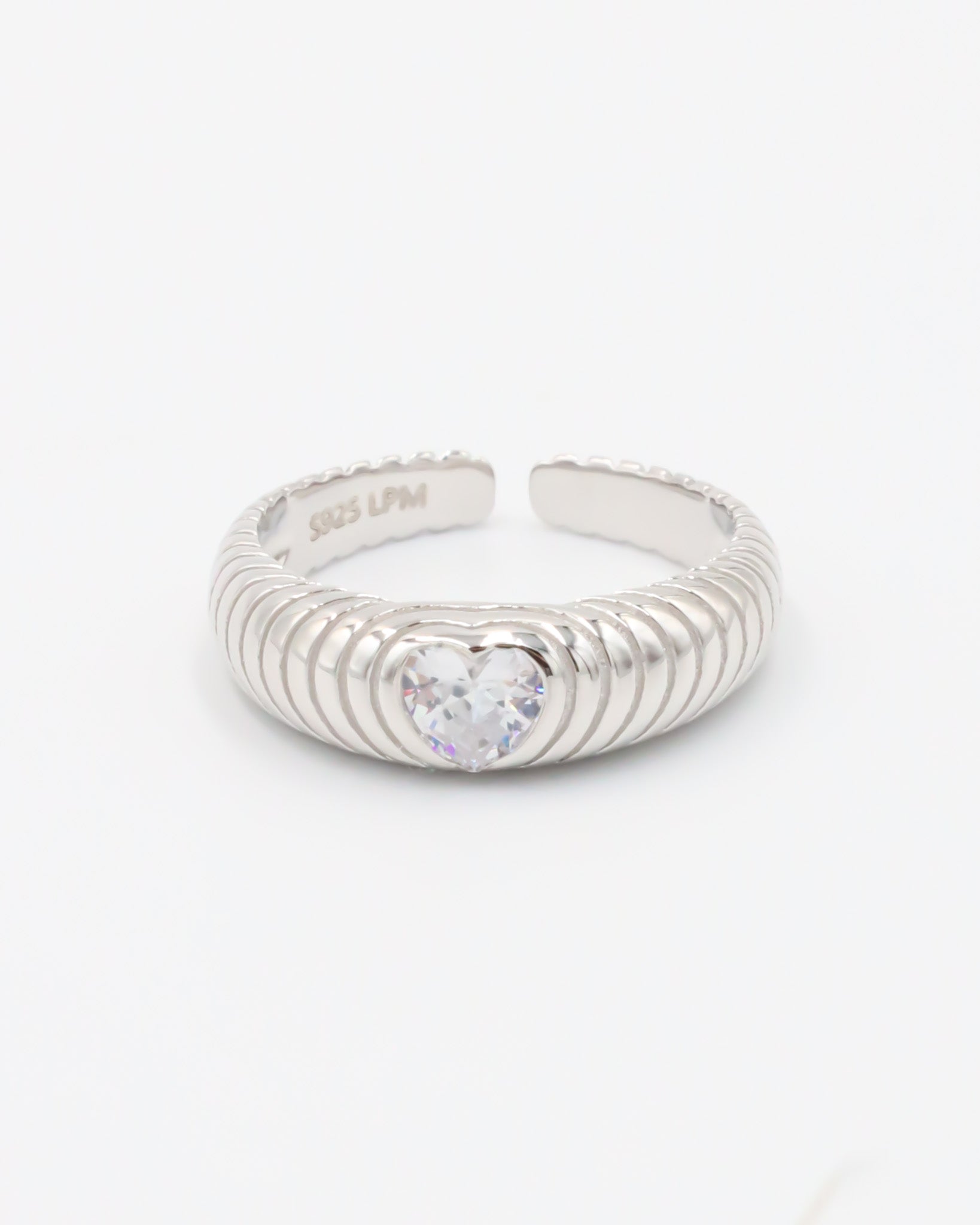 A silver ring with a heart-shaped stone in the center, featuring a textured band and a brightly colored stone.