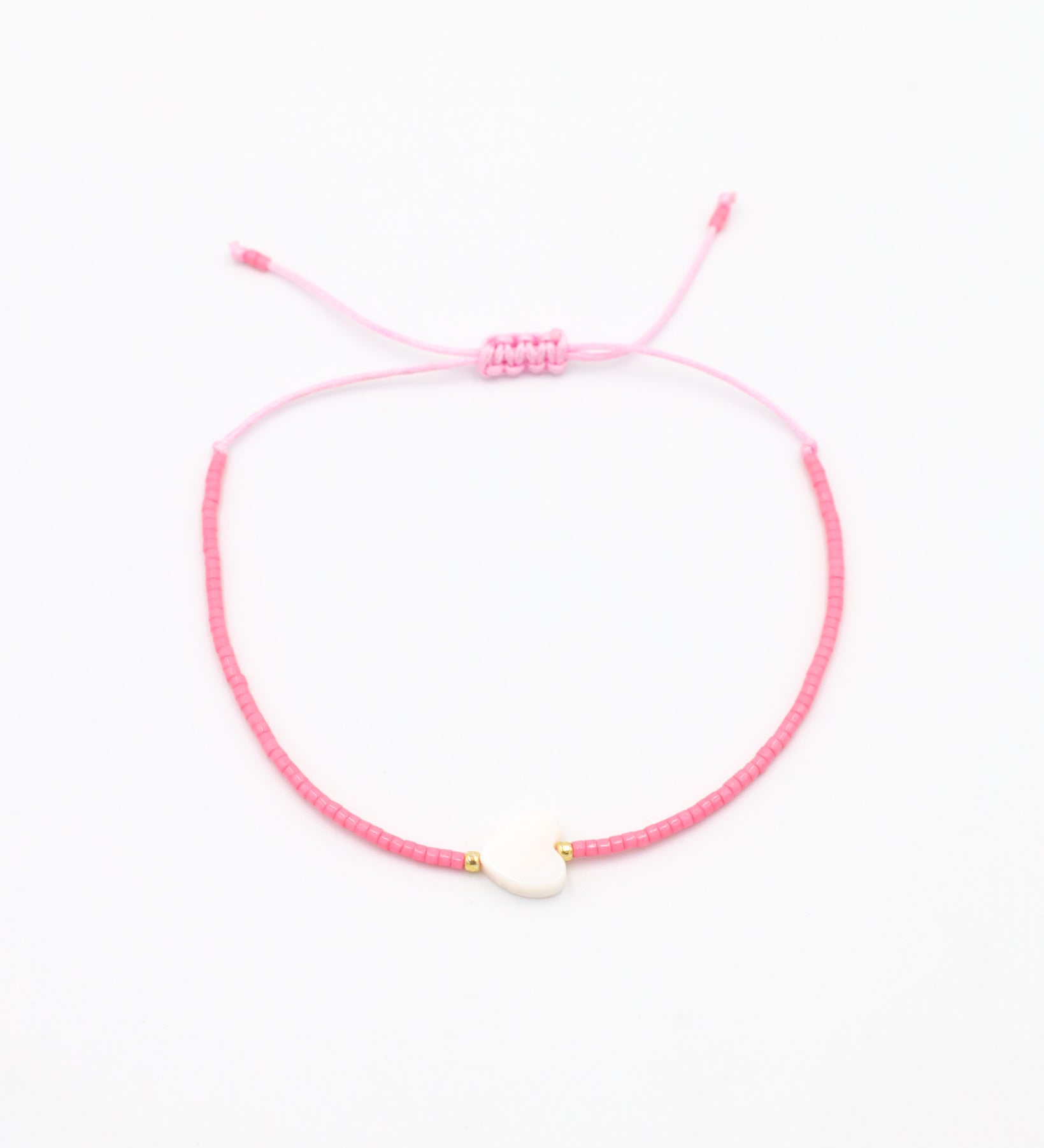 An adjustable pink bracelet with gold accents and a heart-shaped charm.