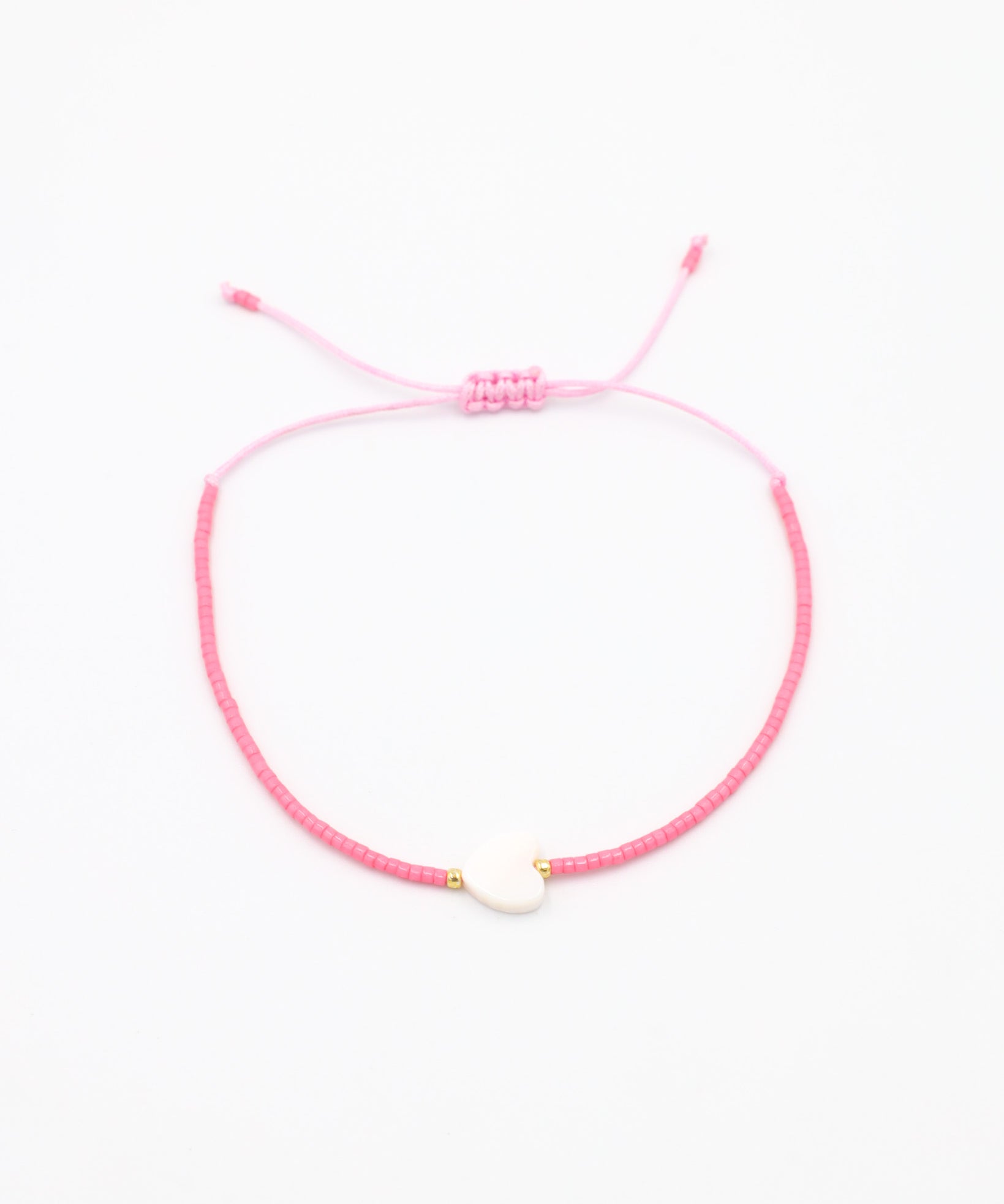 An adjustable pink bracelet with gold accents and a heart-shaped charm.