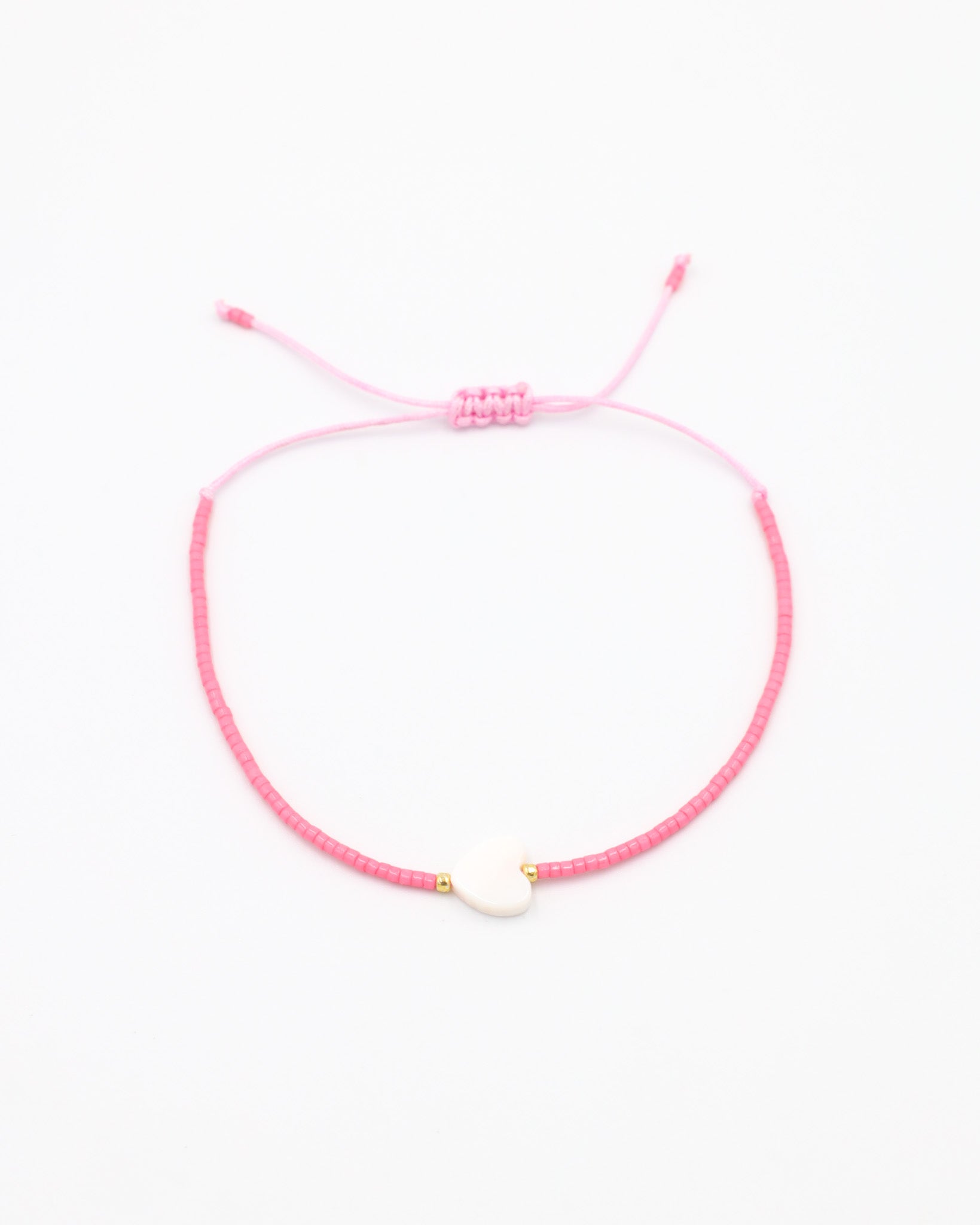 An adjustable pink bracelet with gold accents and a heart-shaped charm.