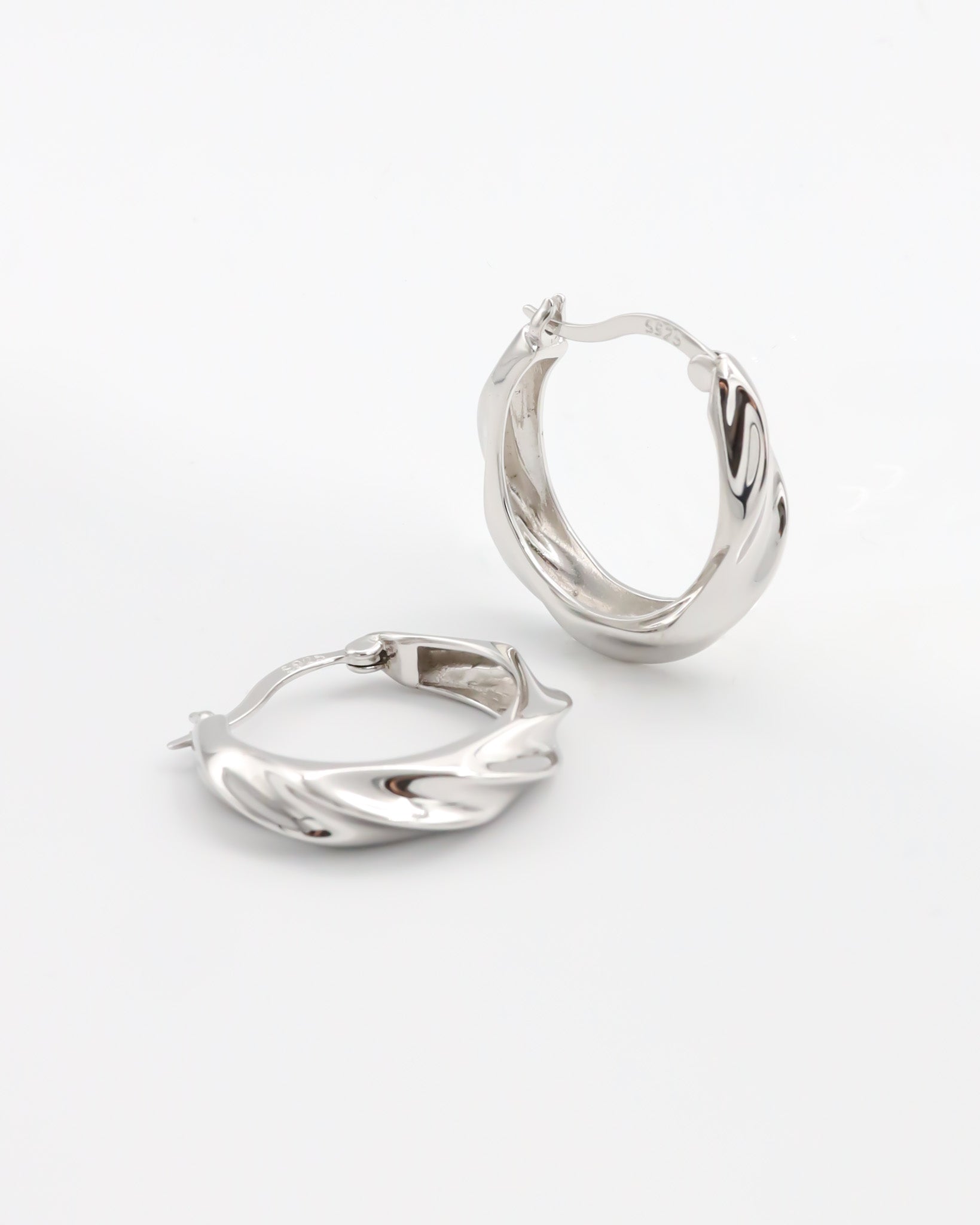 A pair of silver hoop earrings with a latch back closure, displayed on a white background.