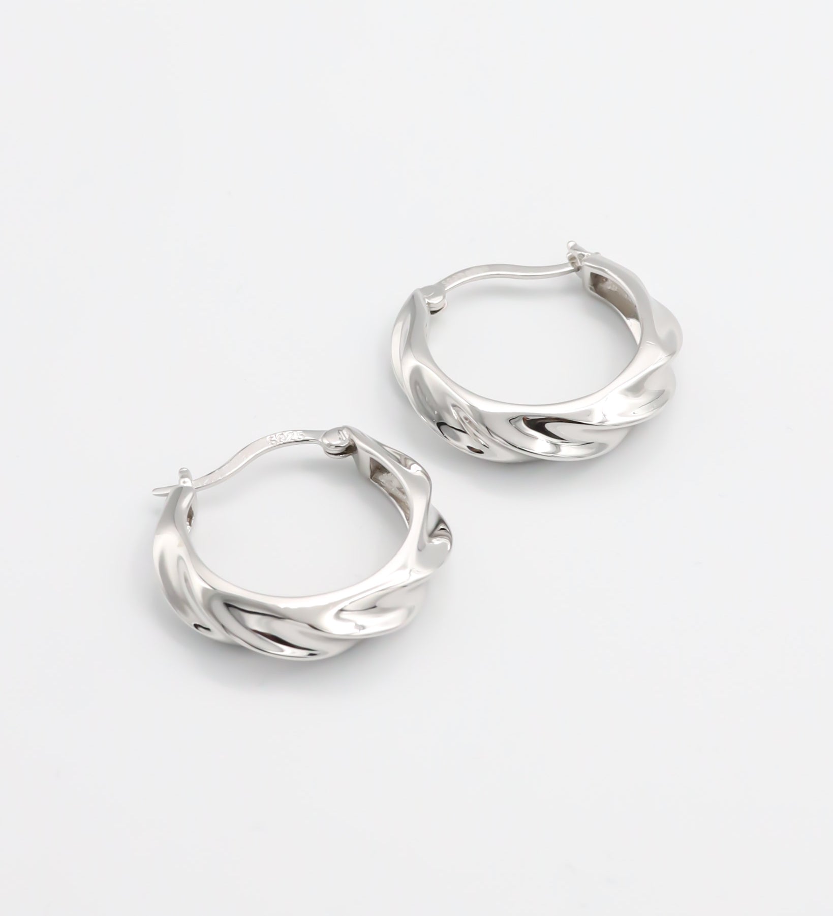 A pair of silver hoop earrings with a latch back closure, displayed on a white background.