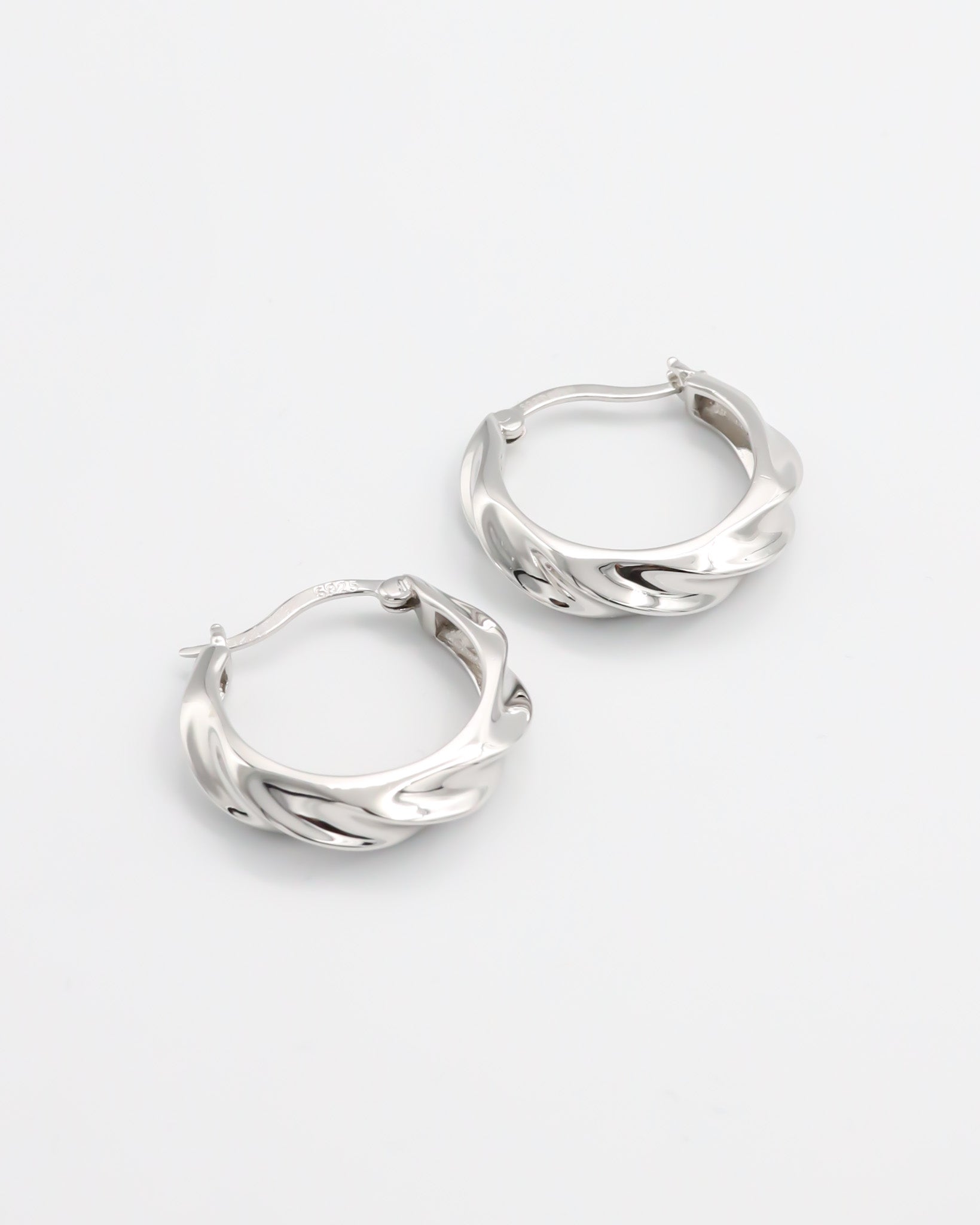 A pair of silver hoop earrings with a latch back closure, displayed on a white background.