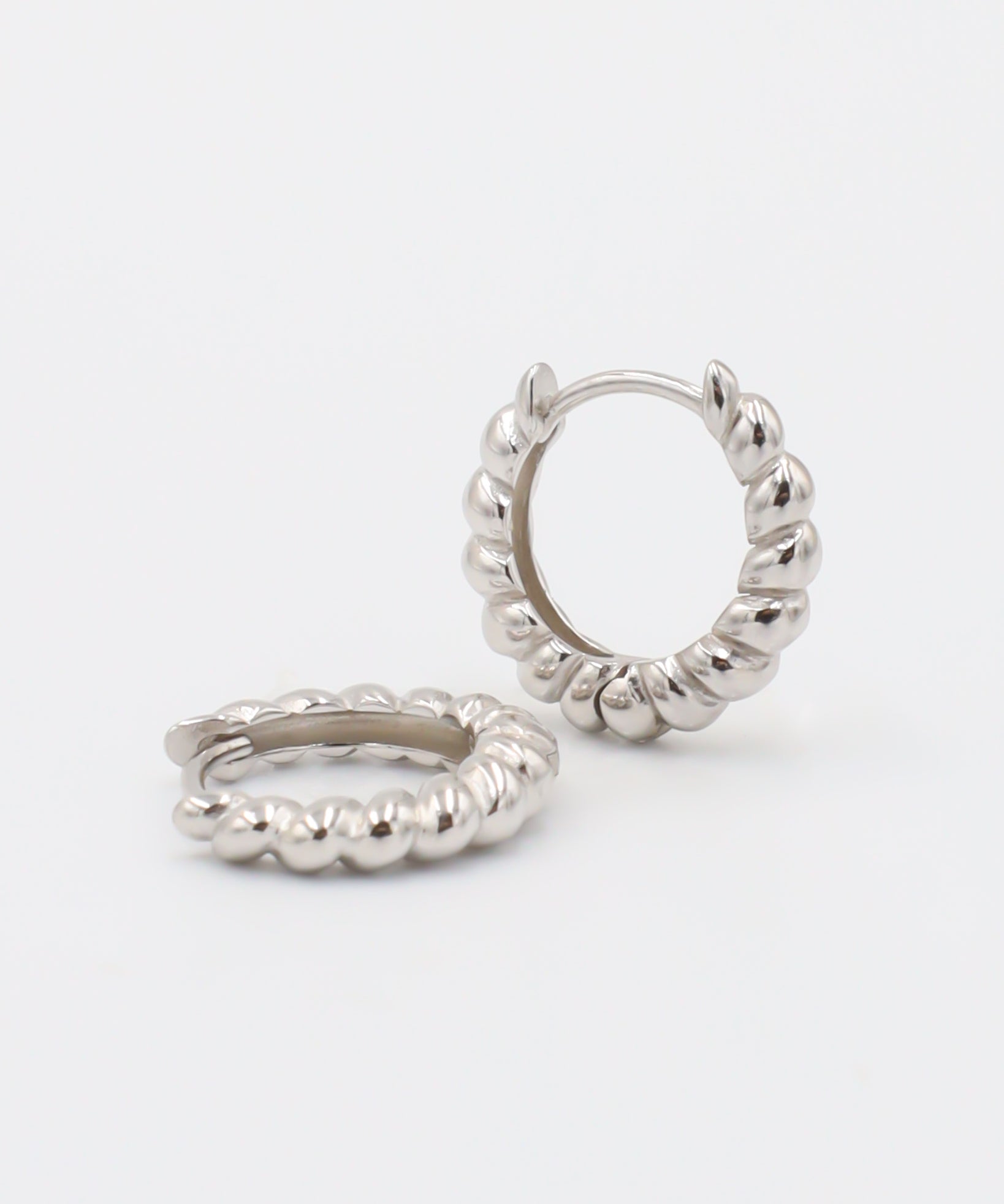 A pair of silver hoop earrings with a hinged clasp, displayed against a white background.