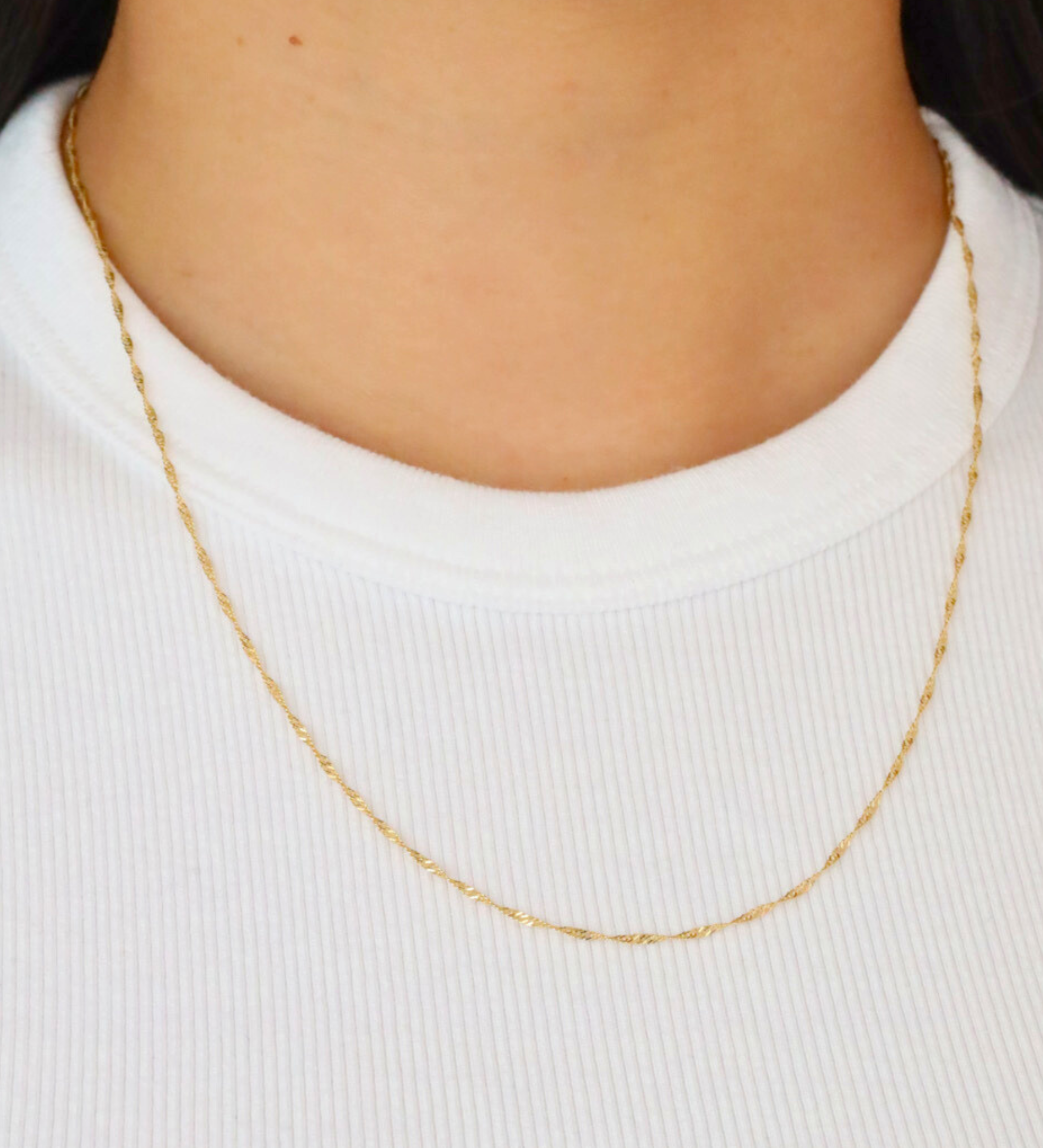 Jamie Gold necklace worn on a model, showcasing the elegant and delicate twisted rope chain on a white shirt.