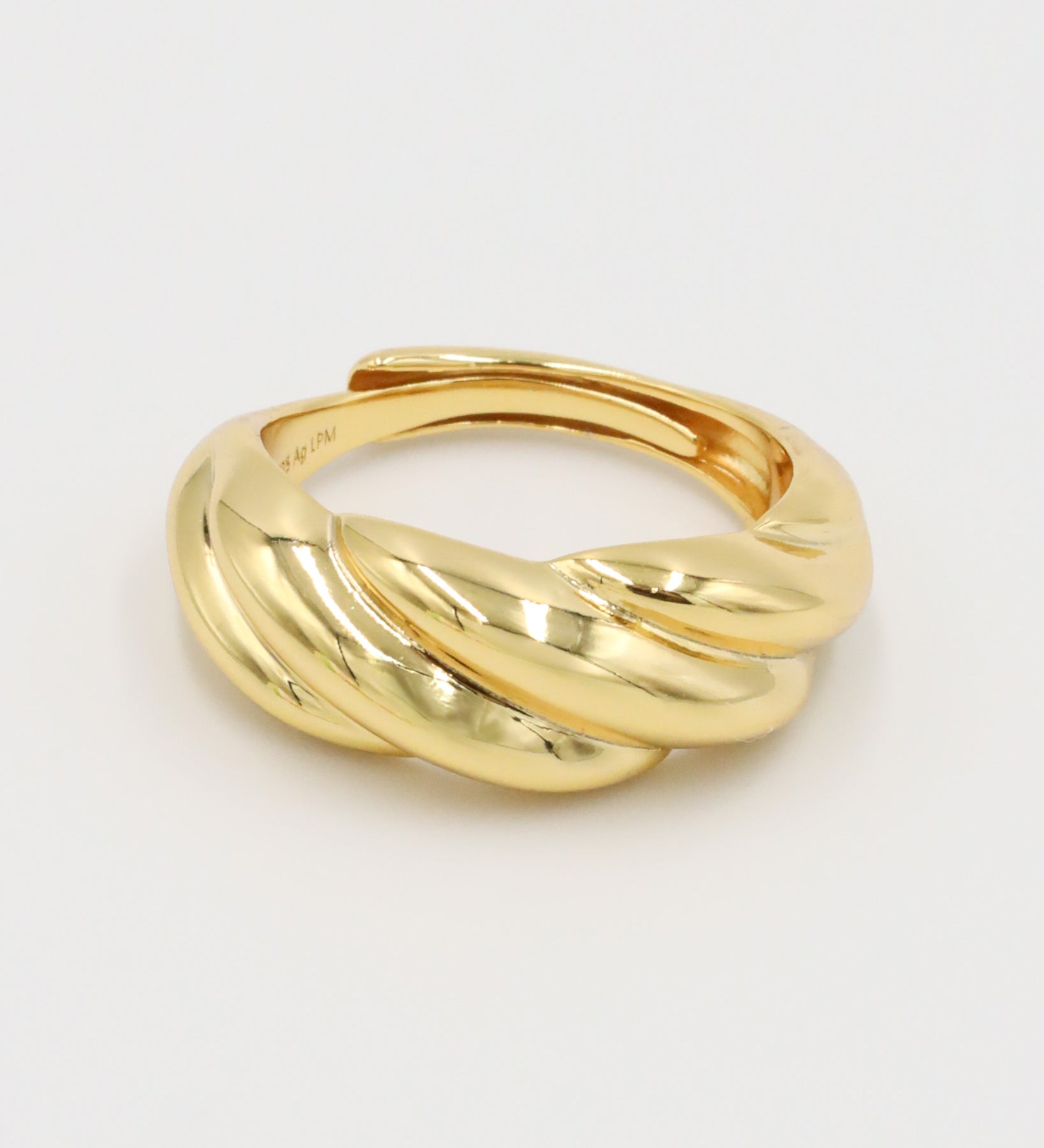A gold-colored ring with a twisted design on a white background