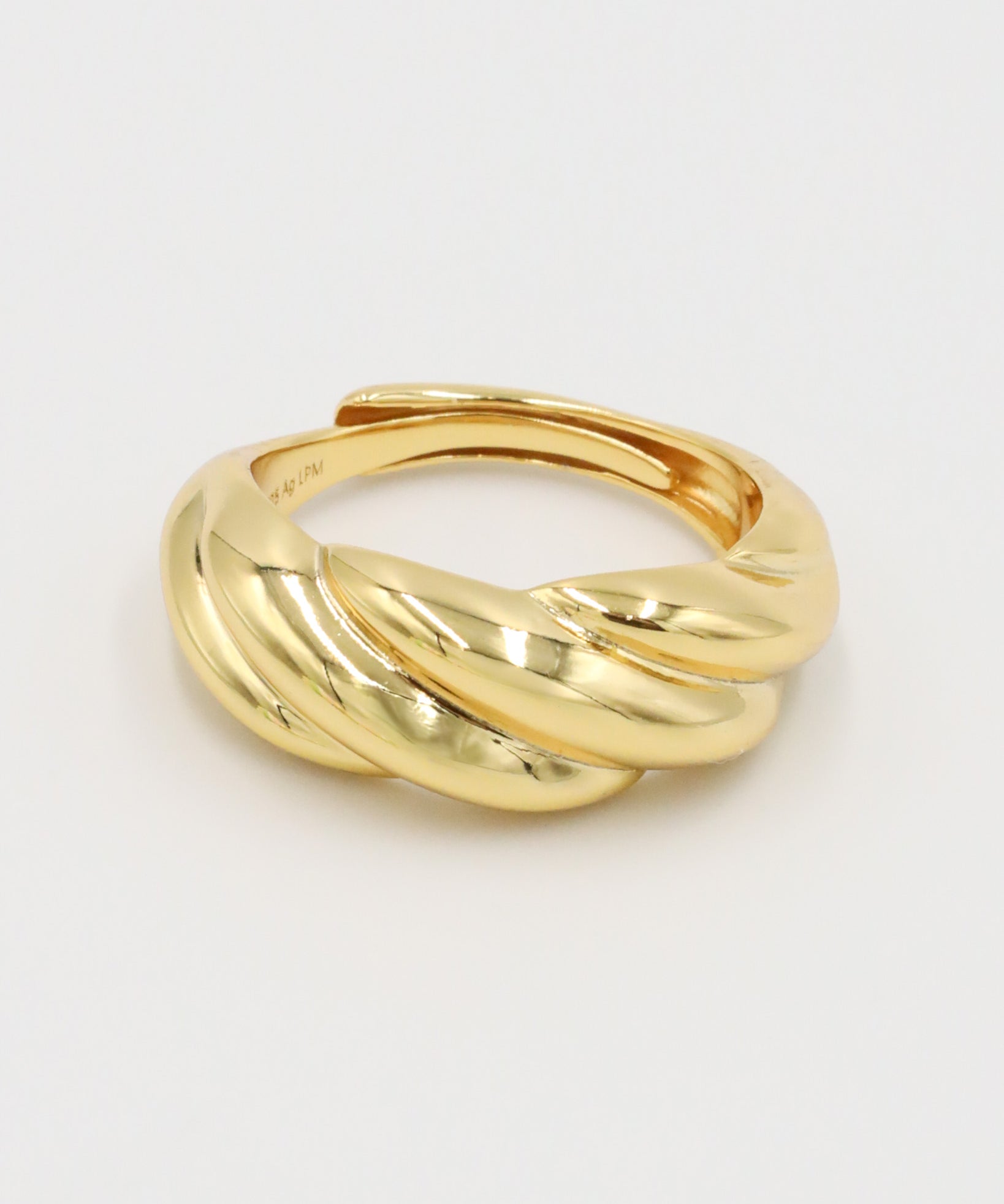 A gold-colored ring with a twisted design on a white background