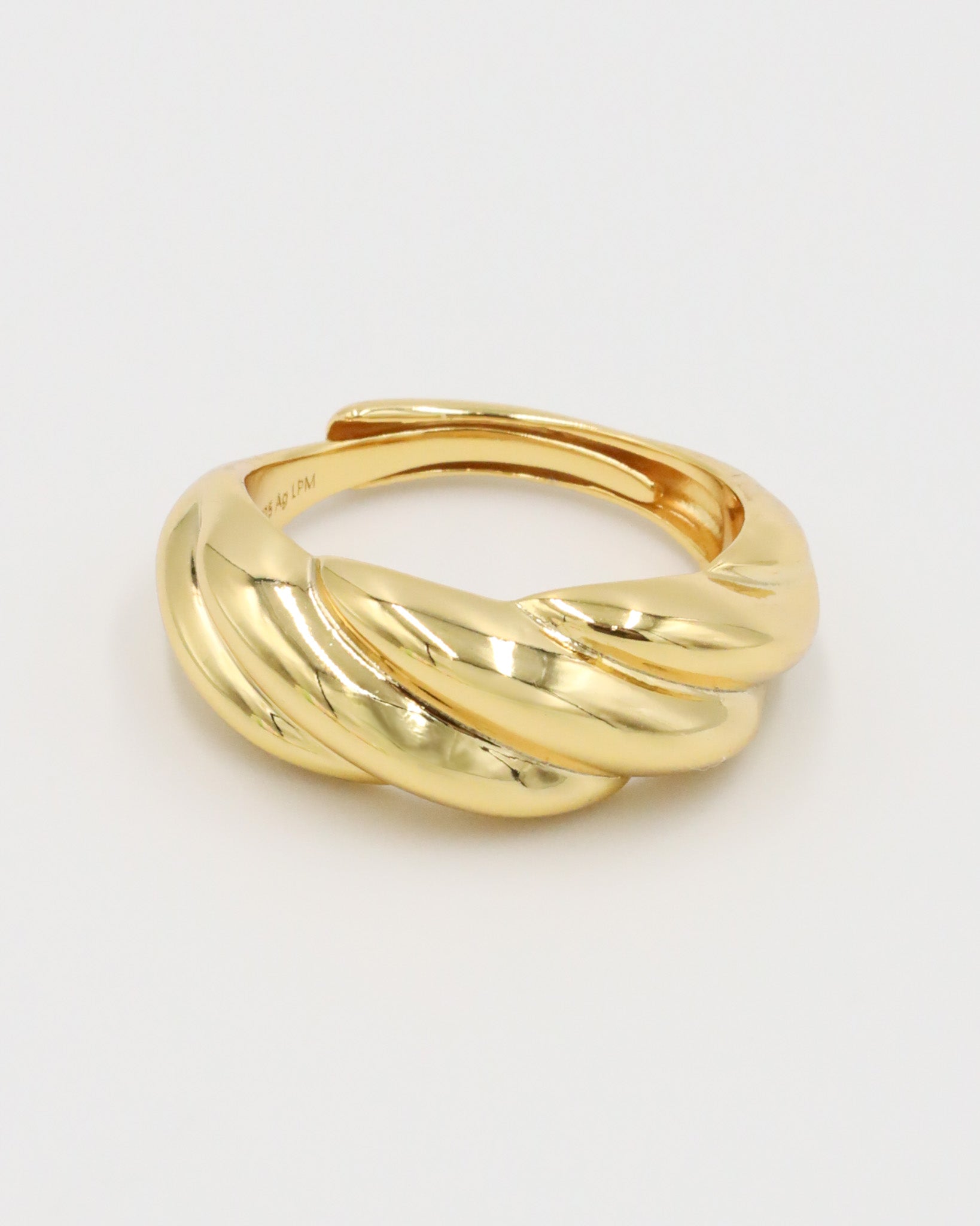 A gold-colored ring with a twisted design on a white background