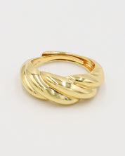 A gold-colored ring with a twisted design on a white background