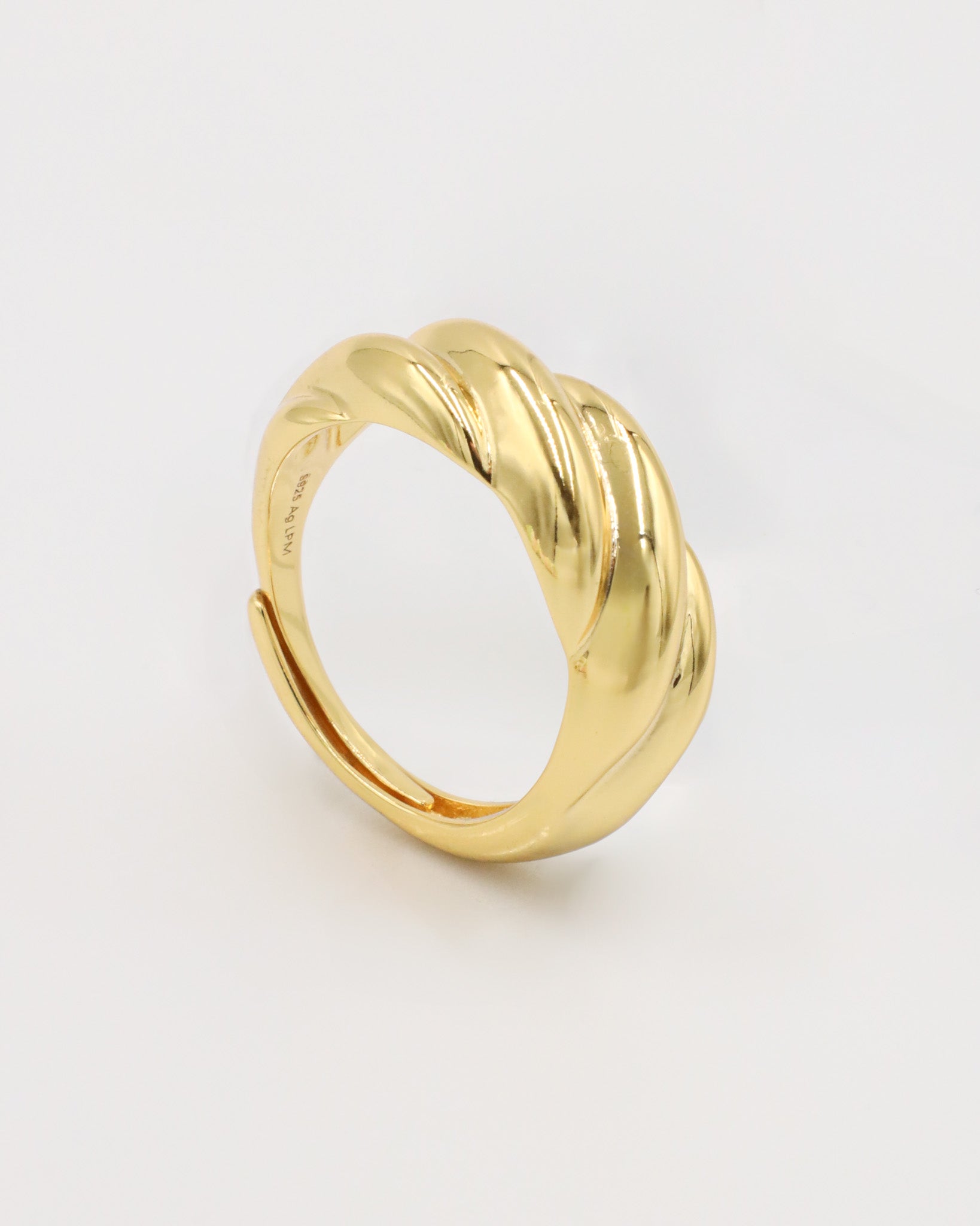 A gold-colored ring with a twisted design standing on a white background